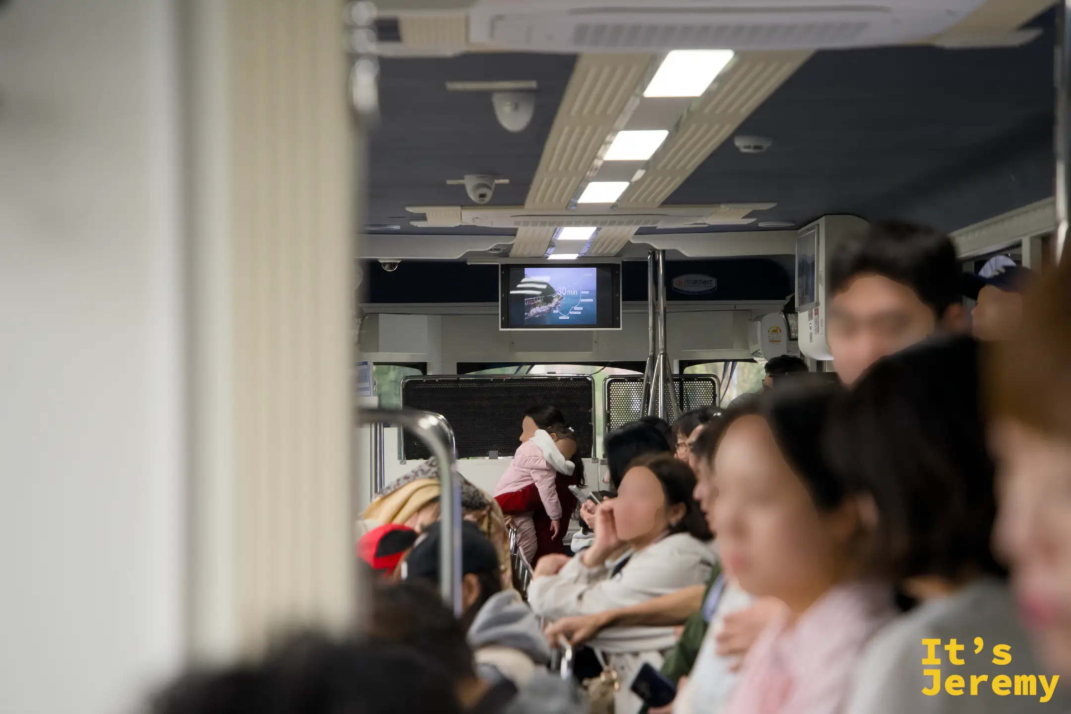 車廂內坐滿乘客，螢幕上顯示著行程約 40 分鐘的提示，氣氛輕鬆熱鬧