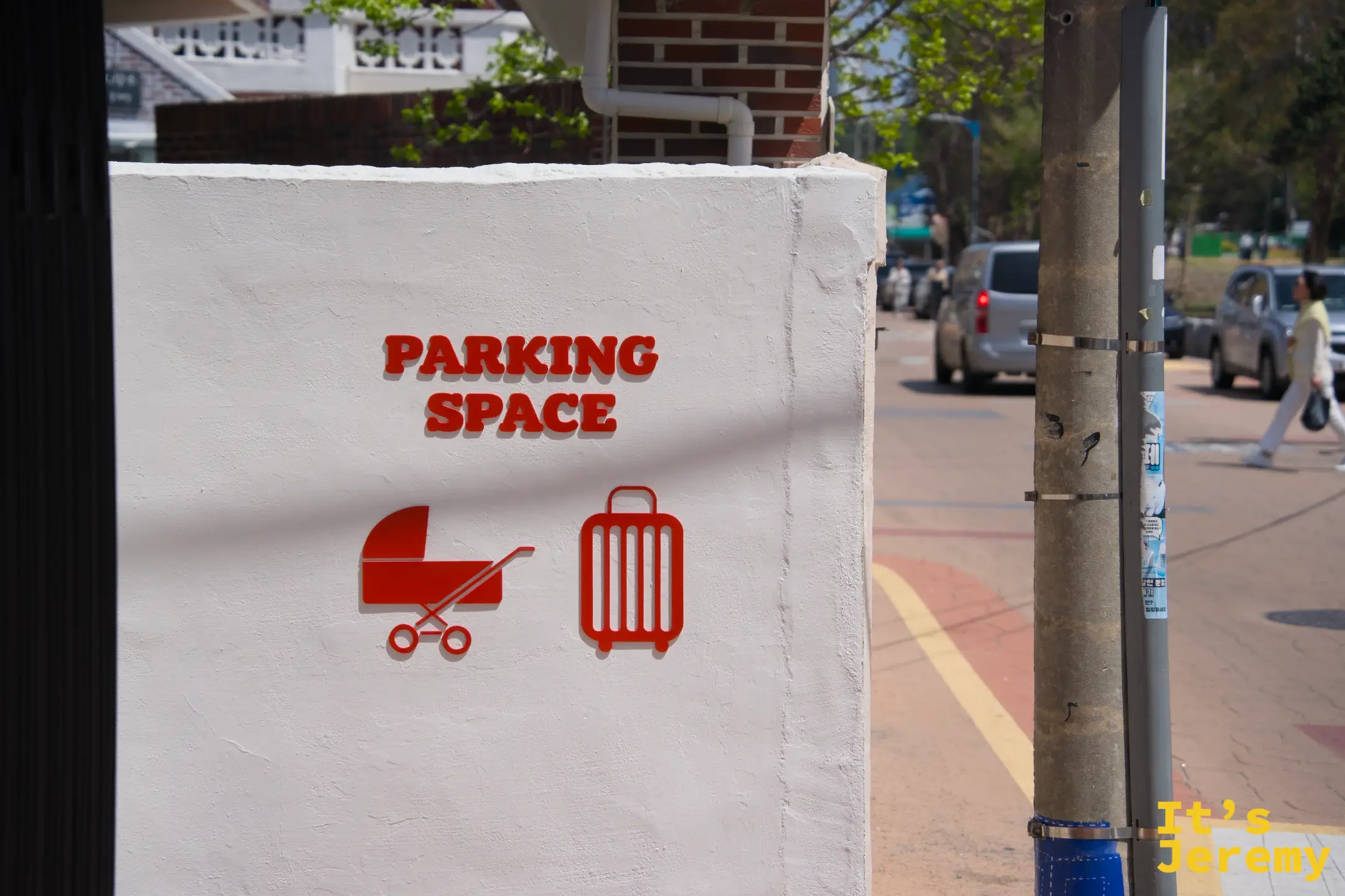 店外牆面上用橘色浮雕標示「PARKING SPACE」並附上嬰兒車與行李箱圖示