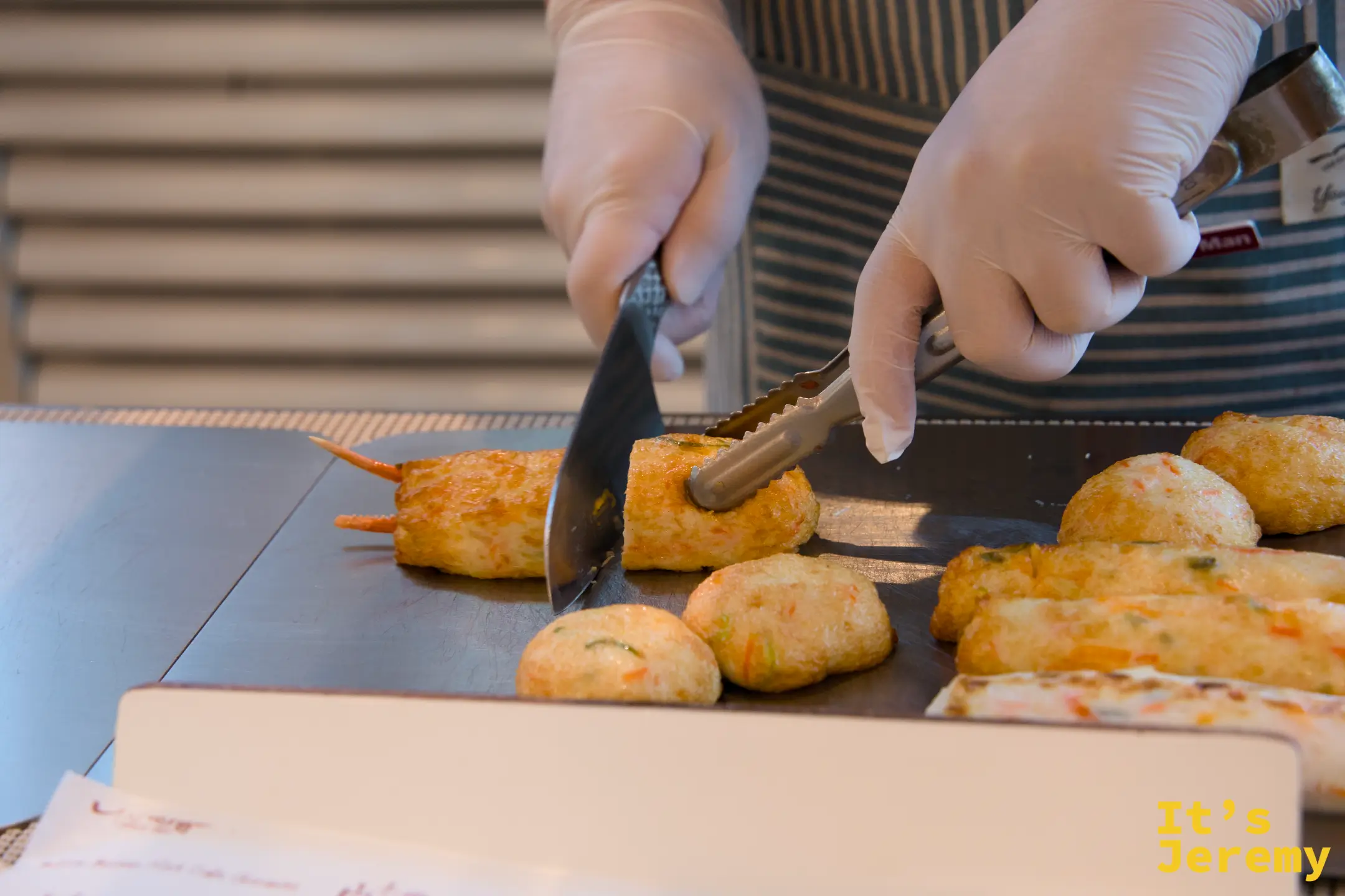 師傅用料理夾在操作台上翻動蝦仁魚板，準備進行切塊