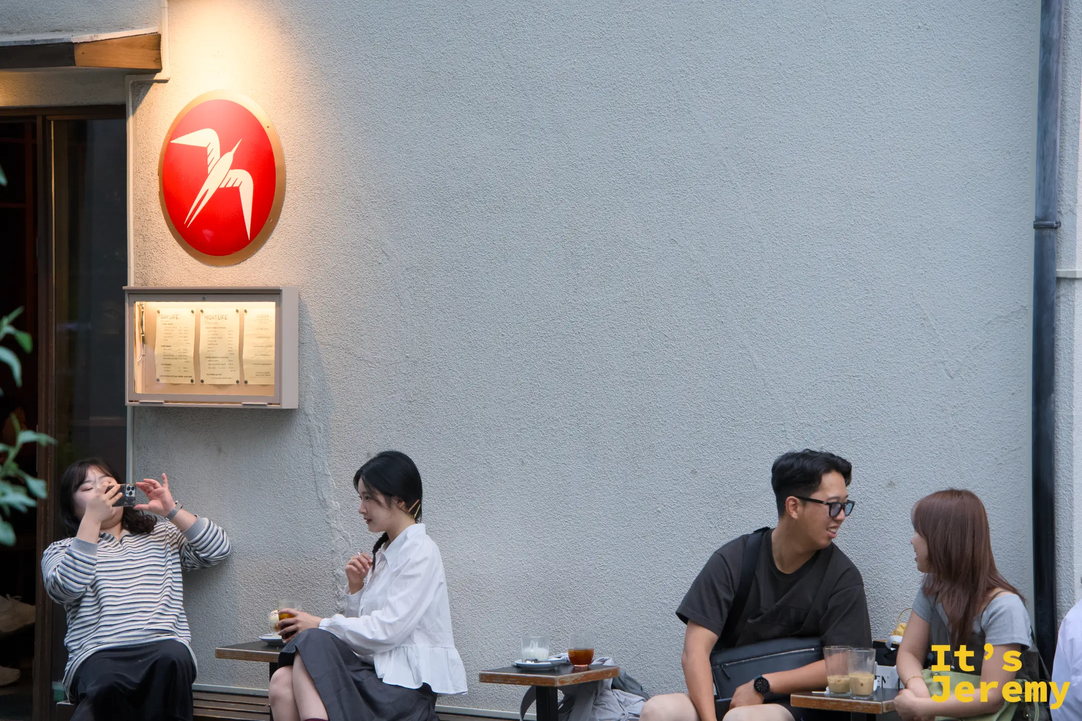 燕子 logo 圓牌近景,底下幾個客人各自發呆喝咖啡,午後的安靜節奏