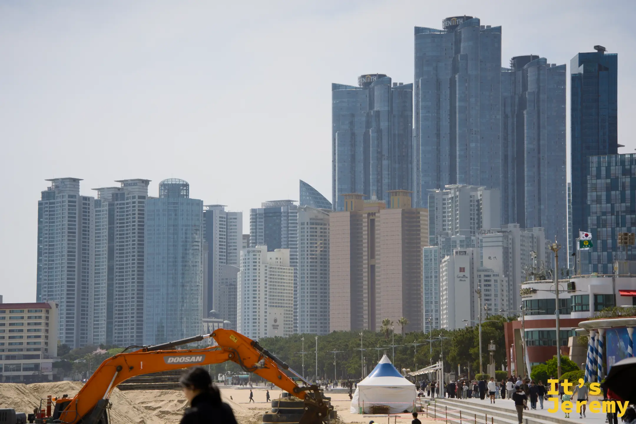 沙雕節開幕前的備戰現場，挖土機負責整理沙面與堆高沙堆，背後是 LCT Zenith 塔群