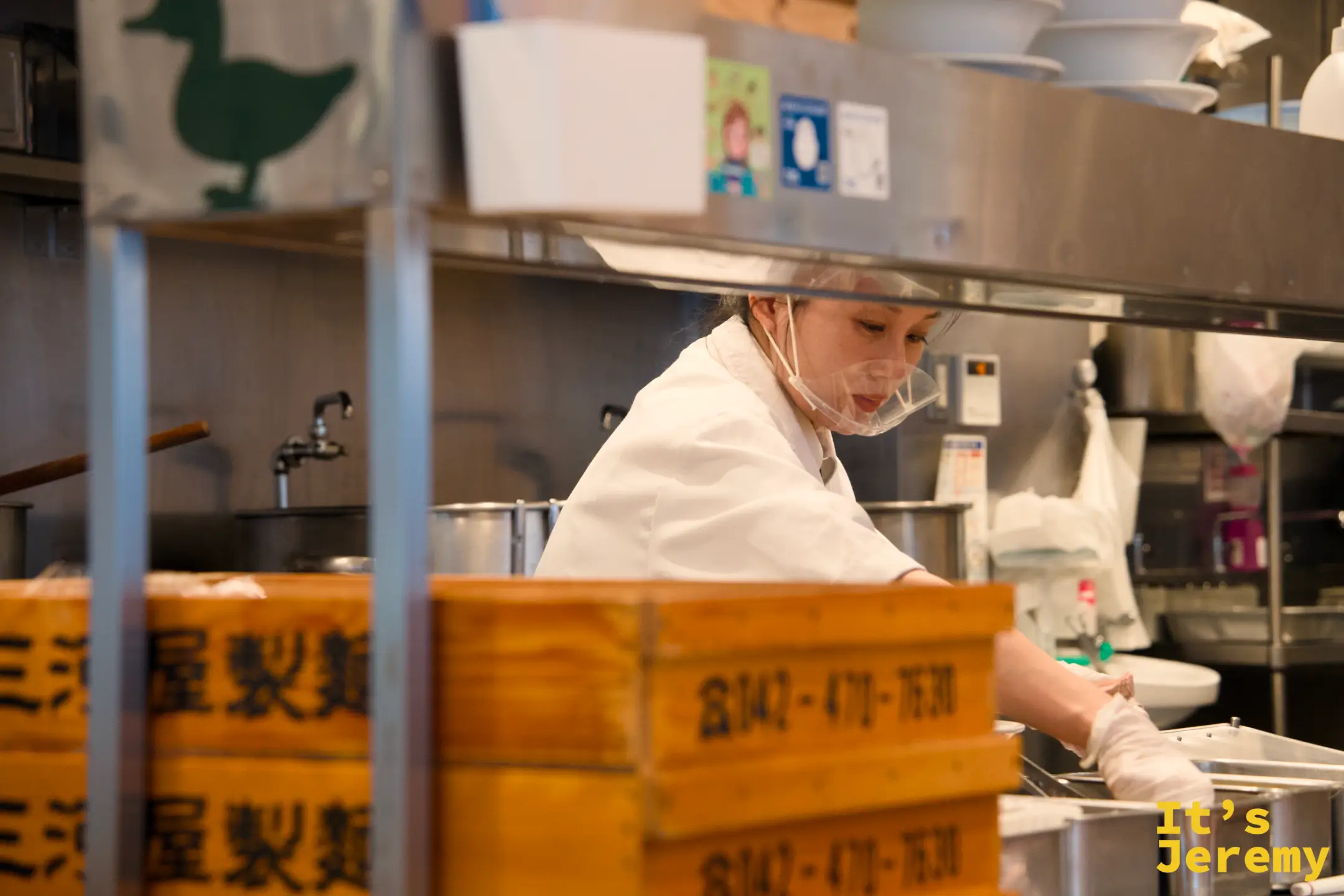 廚房工作人員認真備料的身影，後方疊著三屋製麵的木製麵箱