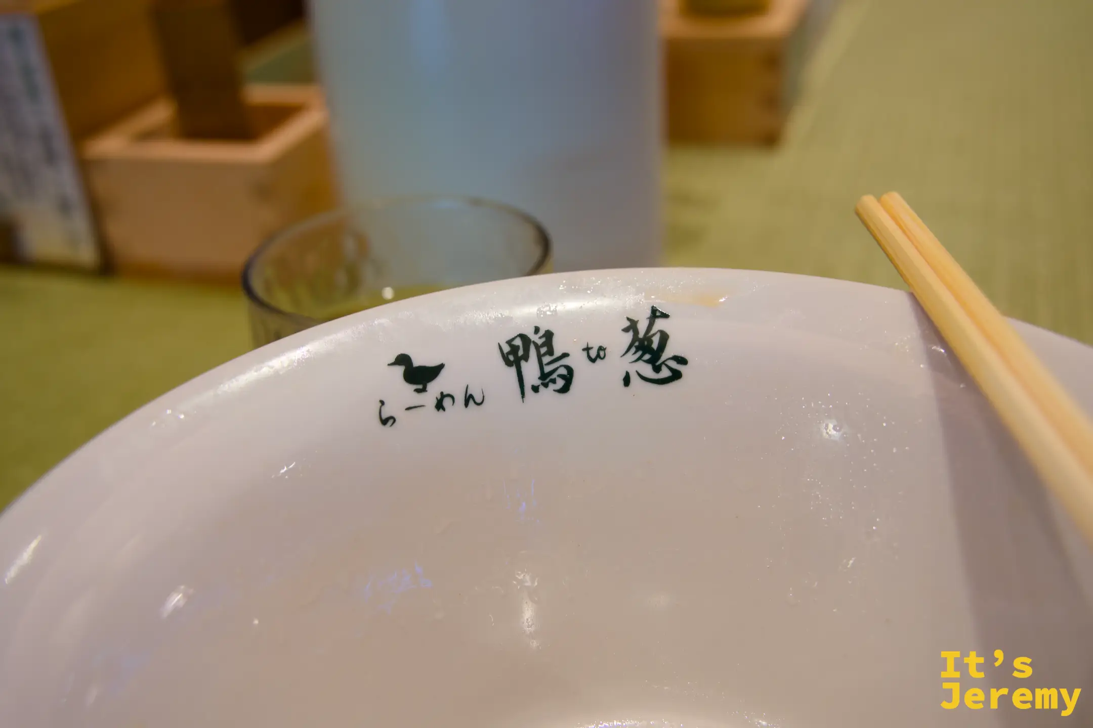 吃完後的空碗，碗沿刻著「らーめん鴨to葱」logo，一雙筷子斜放