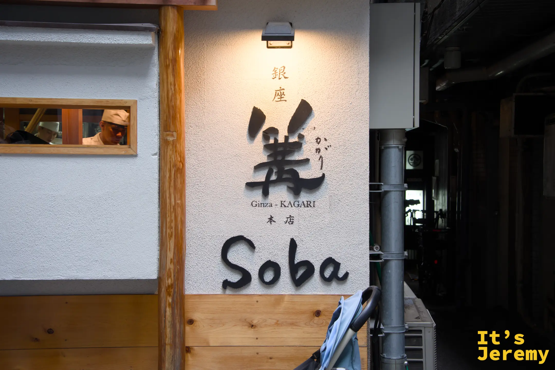 門面外牆，「銀座 篝 Ginza-KAGARI 本店 Soba」字樣清晰，廚師透過小窗隱約可見