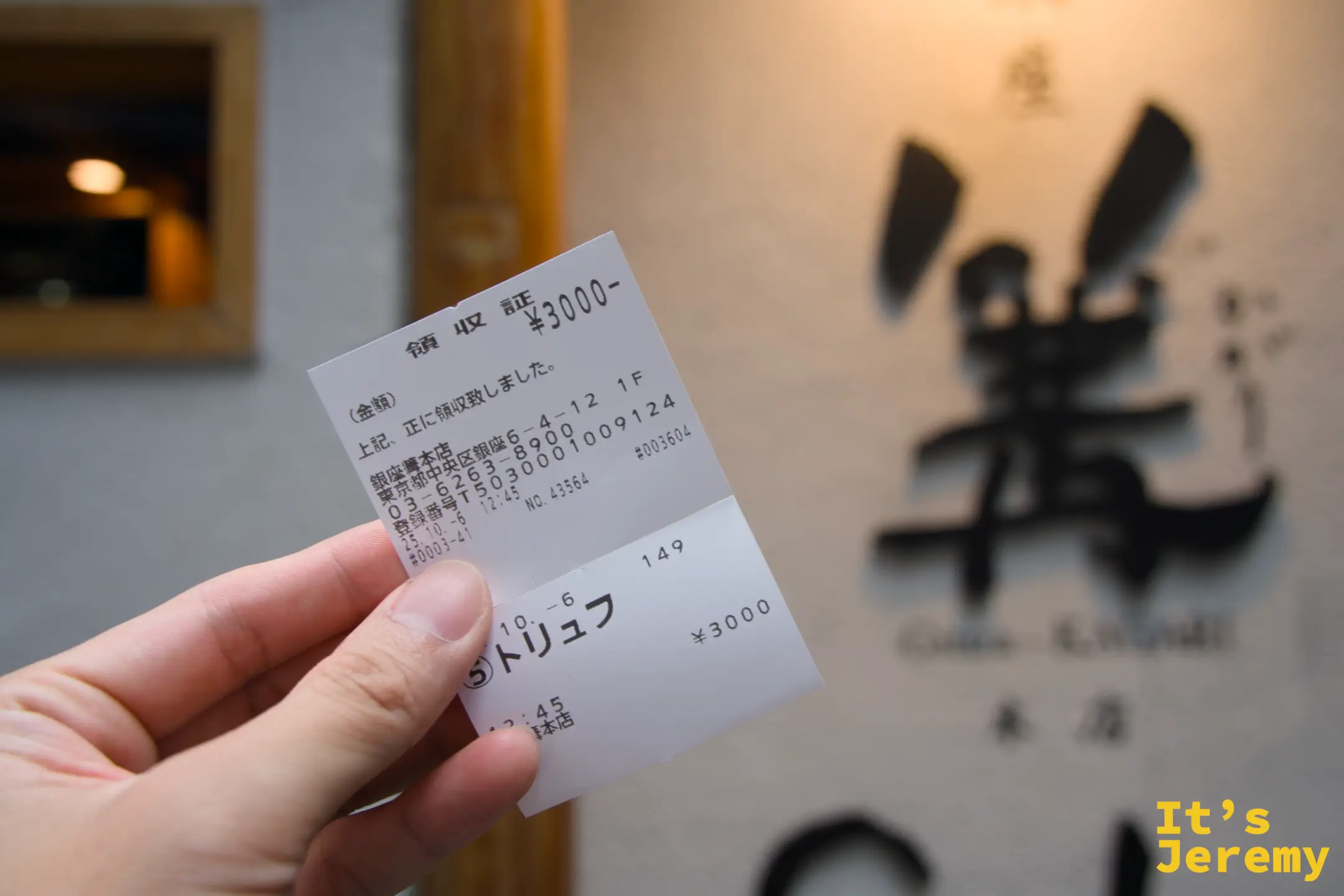 手持餐券，上方標注¥3000與「トリュフ」，背景是店家外牆