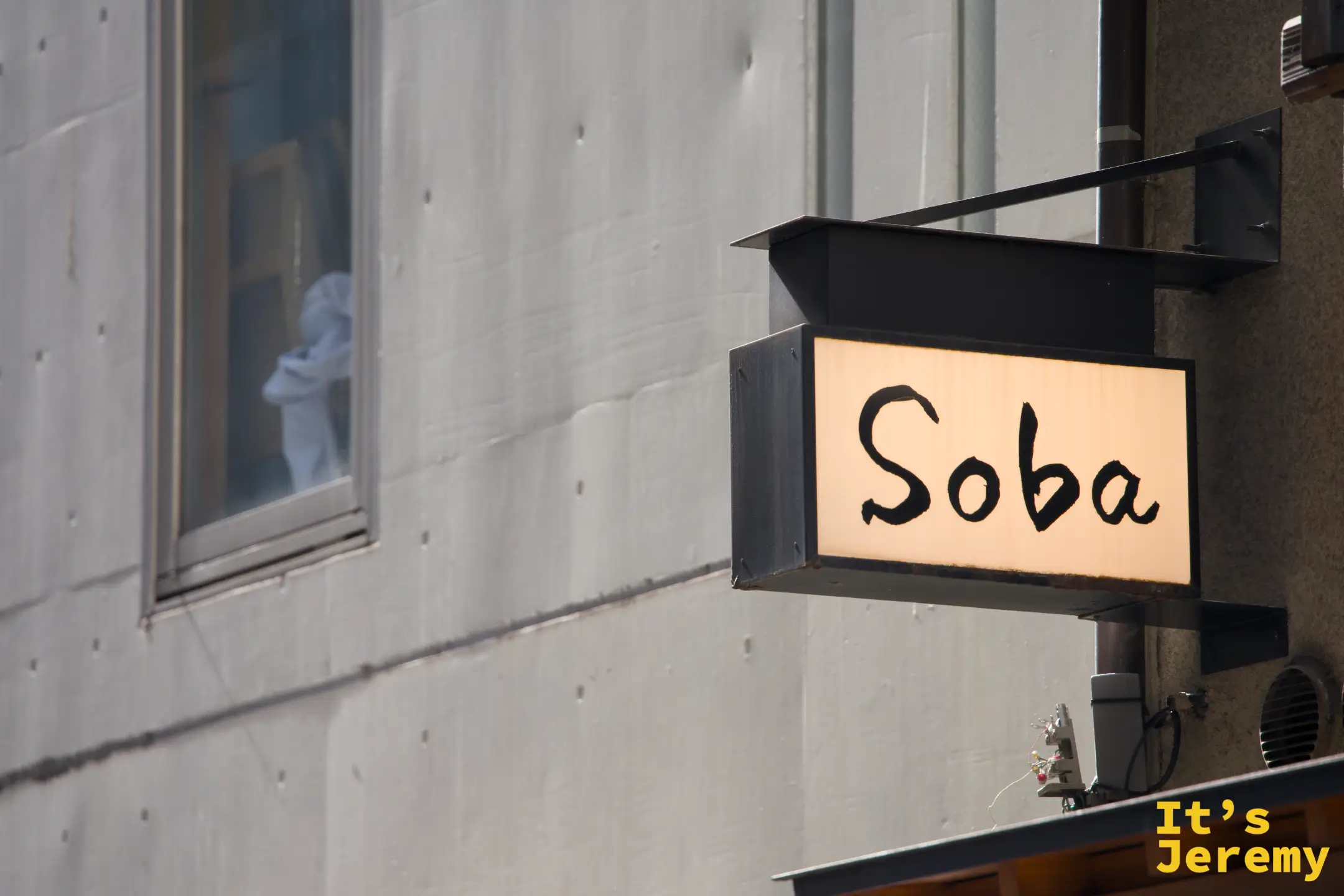 白天街道上看到的「Soba」招牌燈箱（黑框白字），是從遠處確認到店的標記