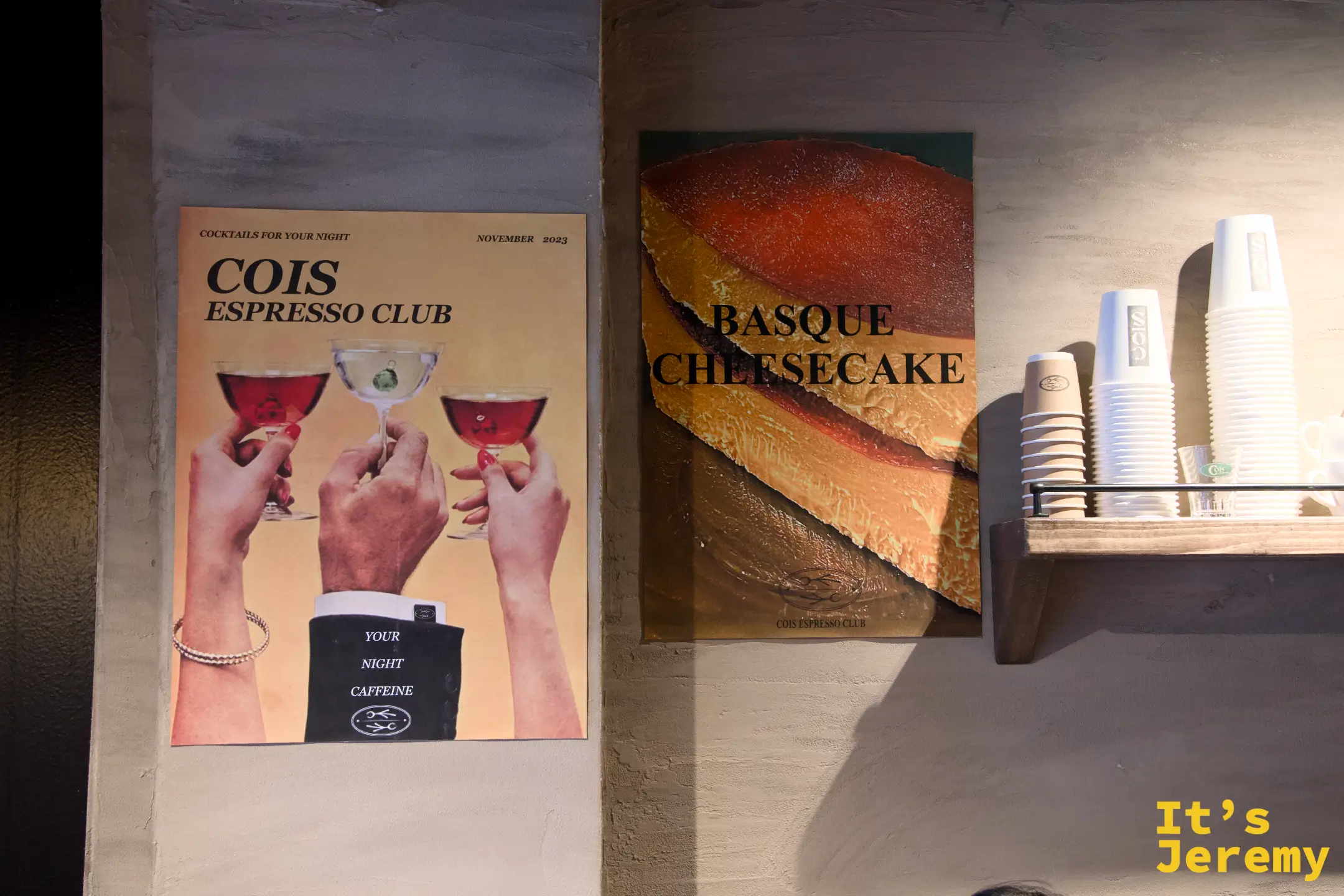 店內牆面的 Cois Espresso Club 調酒海報與巴斯克起司蛋糕海報並排,是這家店日咖夜酒概念最直白的宣示