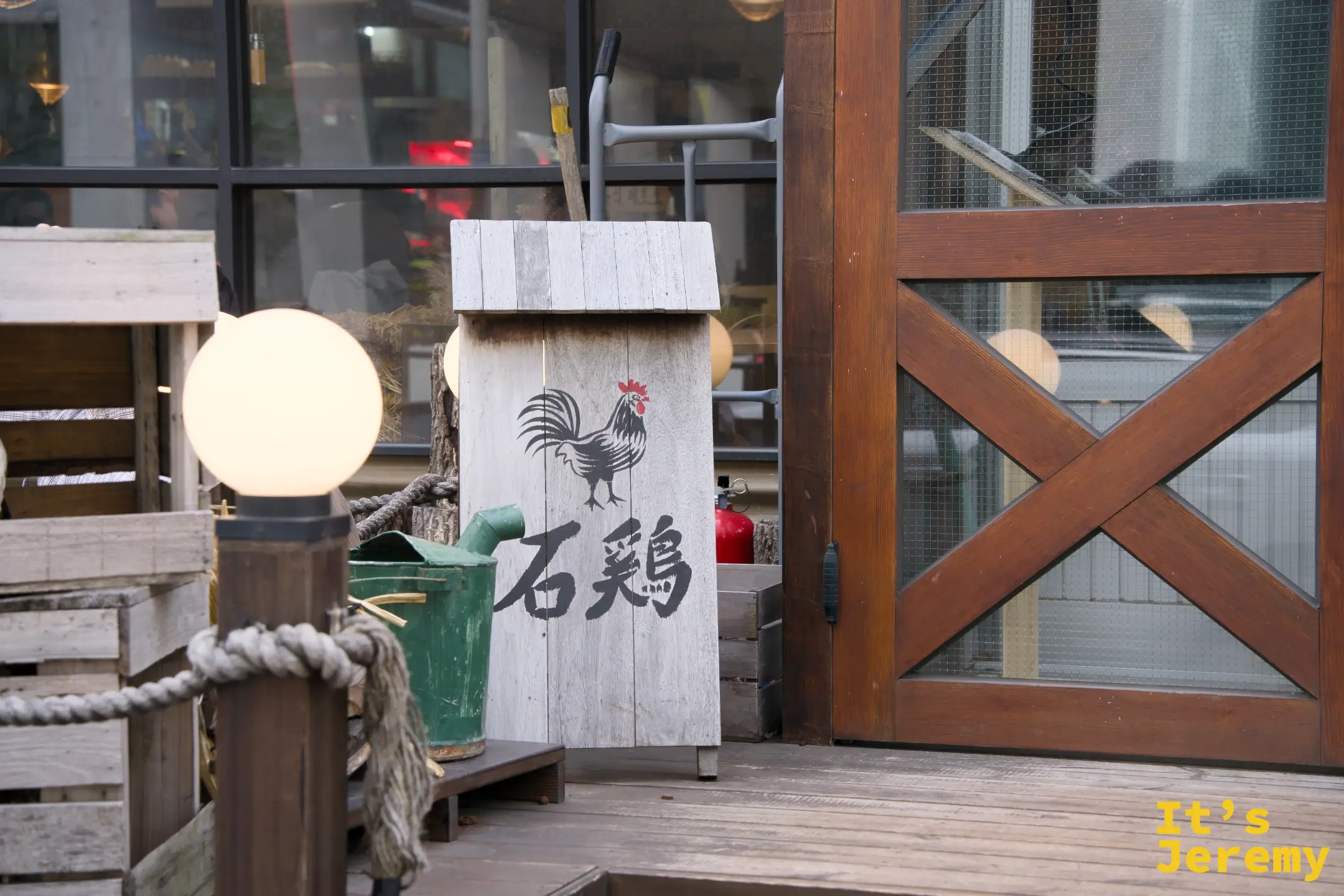 店門口以「石雞」漢字刻在木牌上，搭配粗麻繩與木箱的農場風陳設