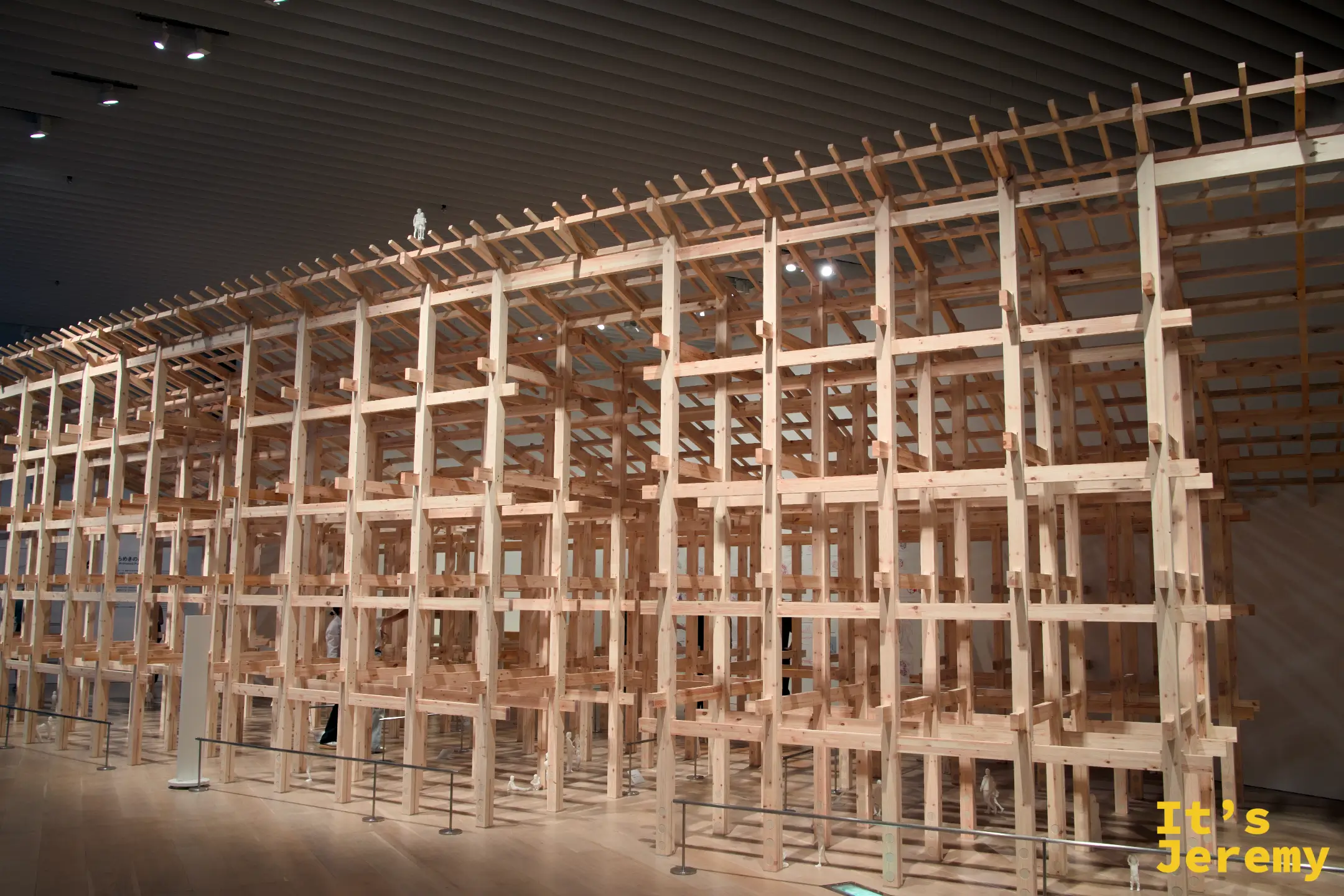藤本壯介個展展廳全景：大型原木骨架裝置填滿整個展廳，高聳至天花板