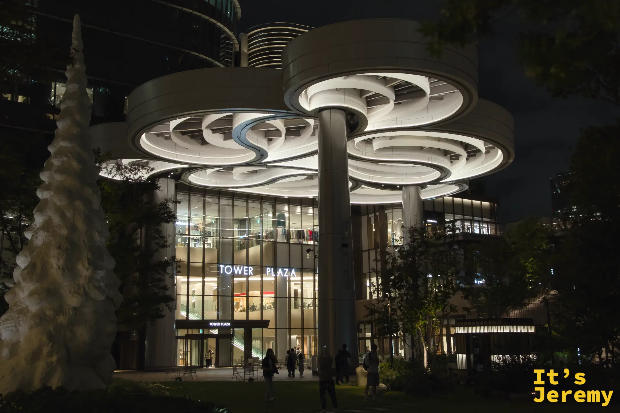 麻布台之丘 Tower Plaza 夜間外觀,入口上方的蘑菇形白色發光燈柱向外延伸,建築線條圓潤有機