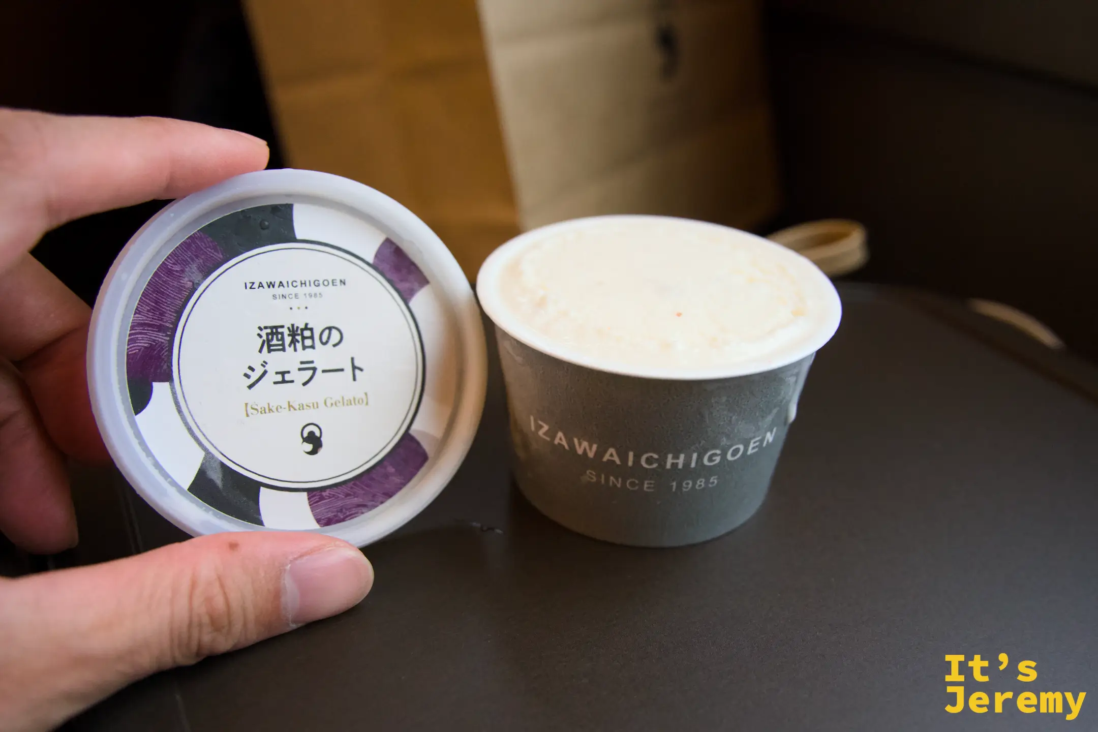 手持打開的酒粕霜淇淋（IZAWAICHIGOEN 品牌），上蓋與杯子分開