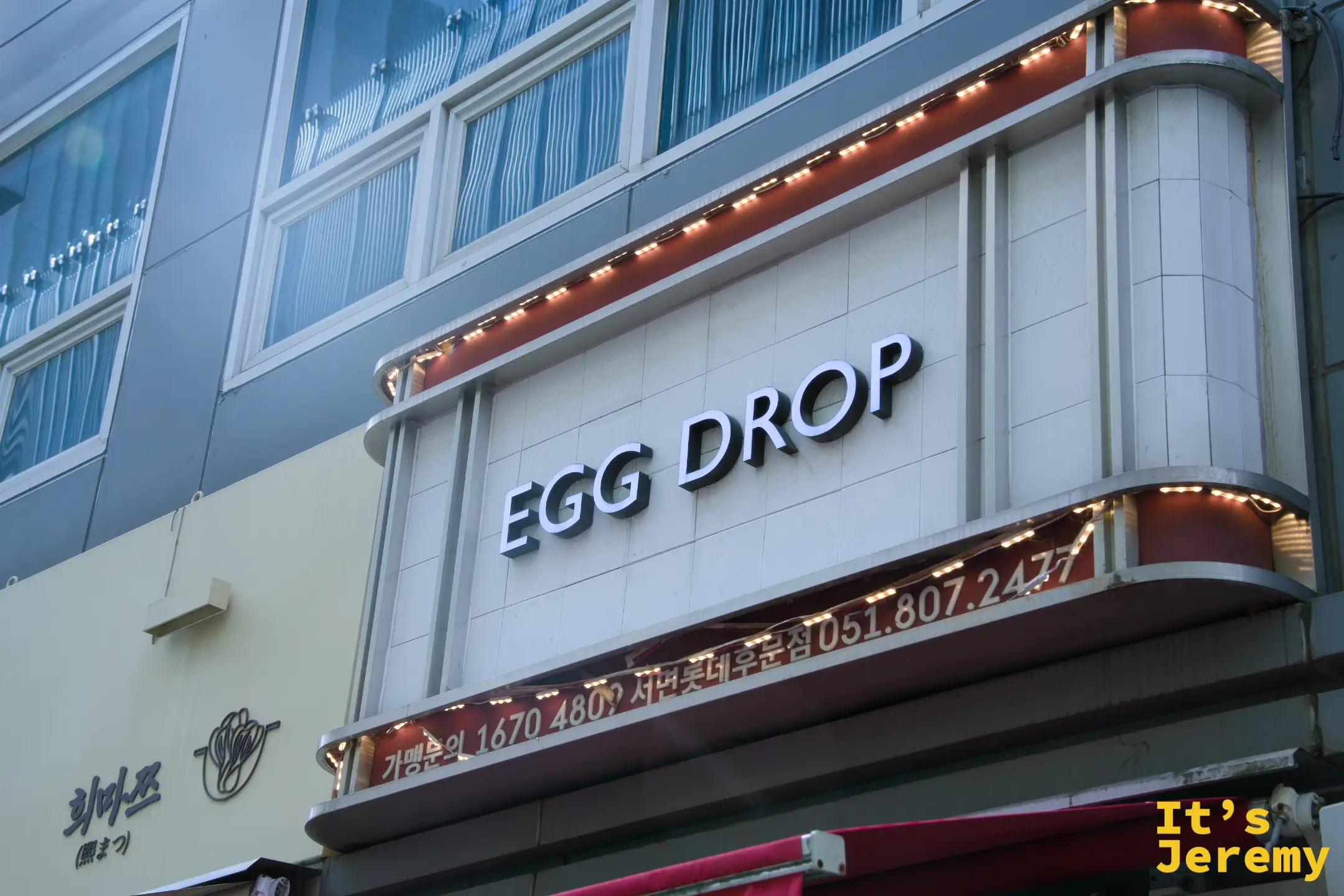 EGG DROP 二樓外牆招牌近拍，暖橙色燈條勾勒出品牌輪廓