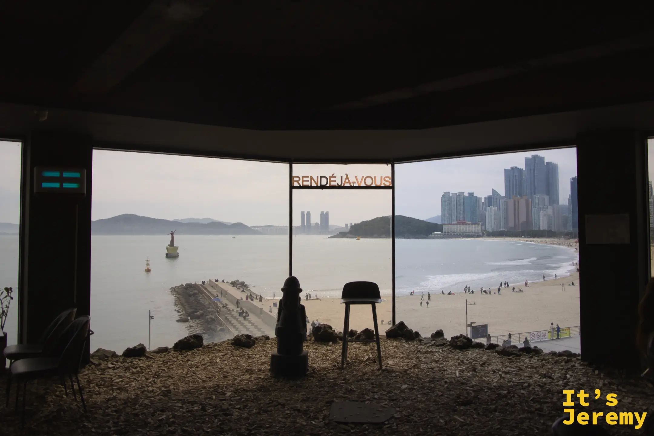 室內陳設：仿傳統石像與北歐設計椅並排，背後是全透明海景窗