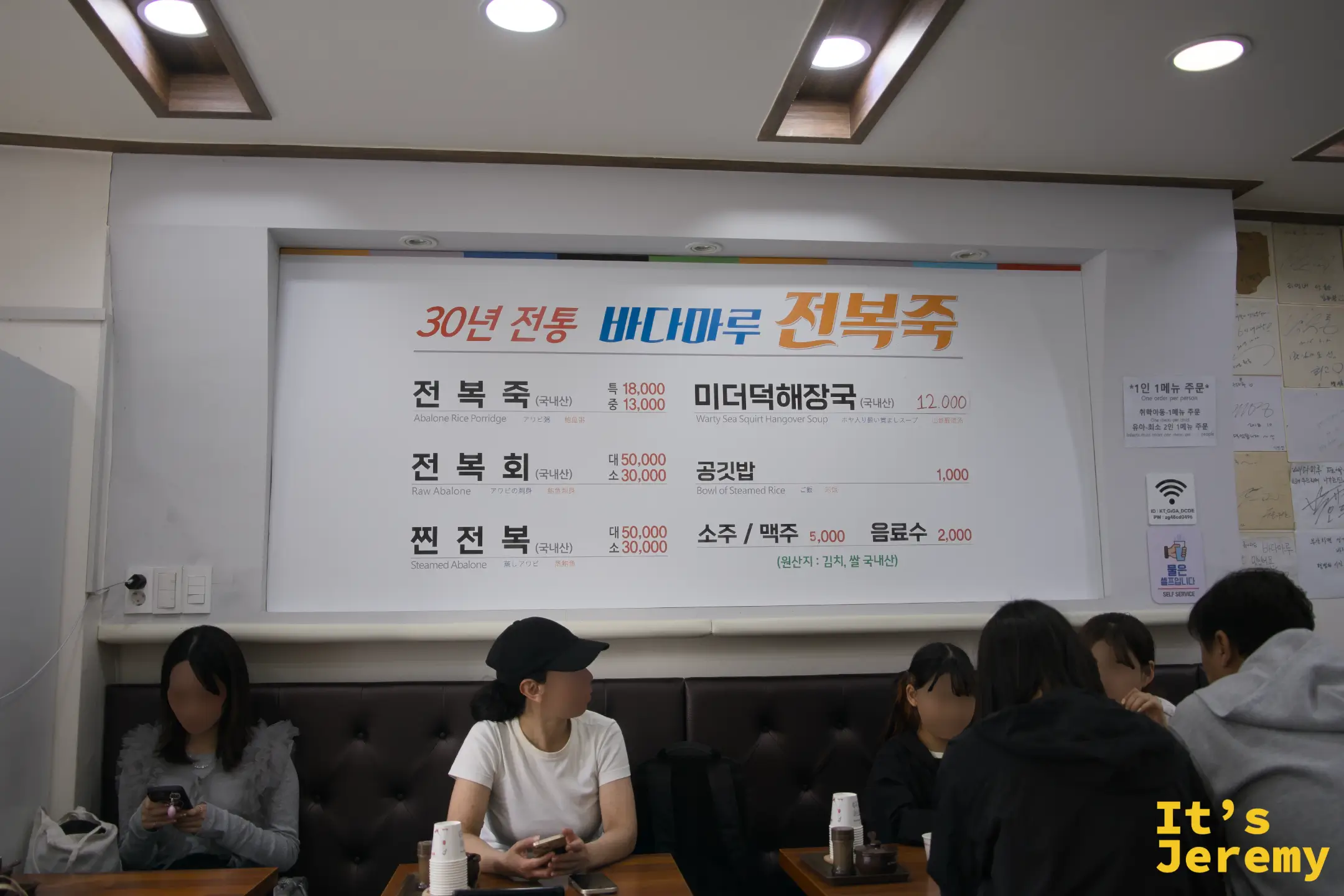 店內牆面菜單，清楚列出每道菜的韓文名稱、英文與日文對照，以及價格