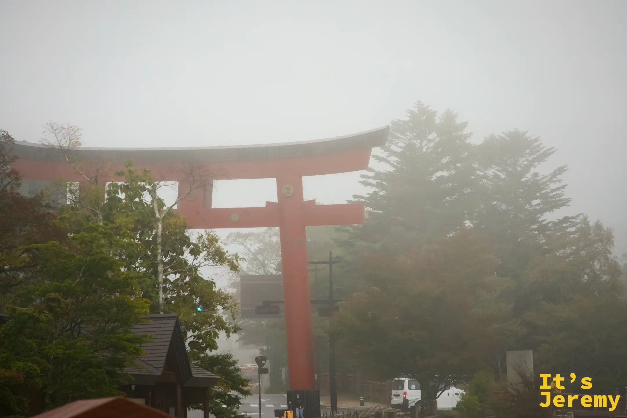 中禪寺湖旁望去，二荒山神社大紅鳥居在樹林霧氣中若隱若現