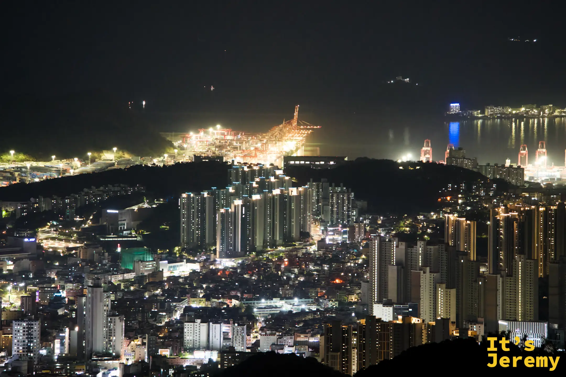 港區設施在夜間橙黃燈光下全力運作，荒嶺山居高臨下可見整片貨櫃場規模