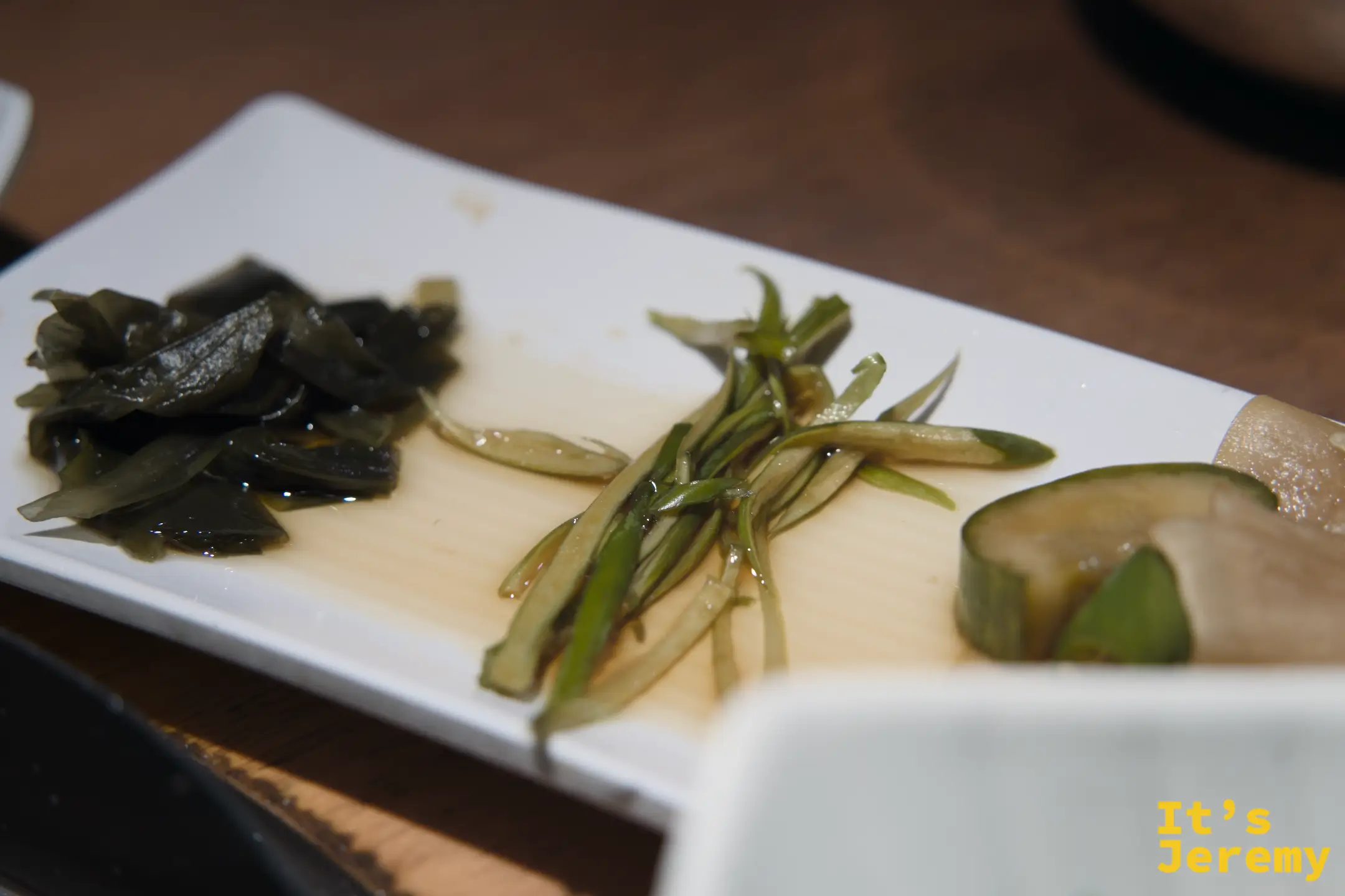 三種醃漬小菜拼盤：海帶、蔥絲與蘿蔔，清爽解膩，是吃烤肉時最佳的口感轉換器