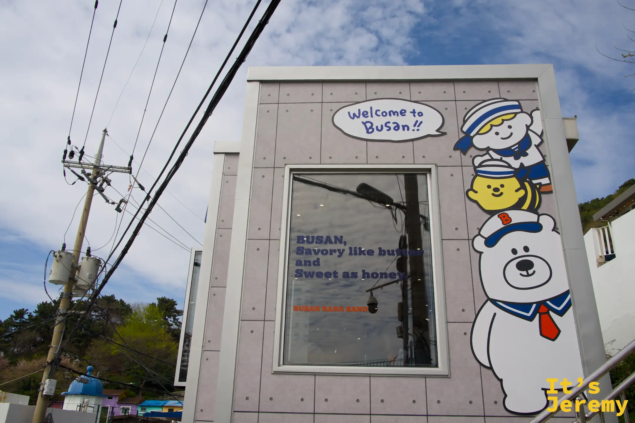 Busan Bada Sand 店外，BOOBA 熊吉祥物角色和「Welcome to Busan!!」標語