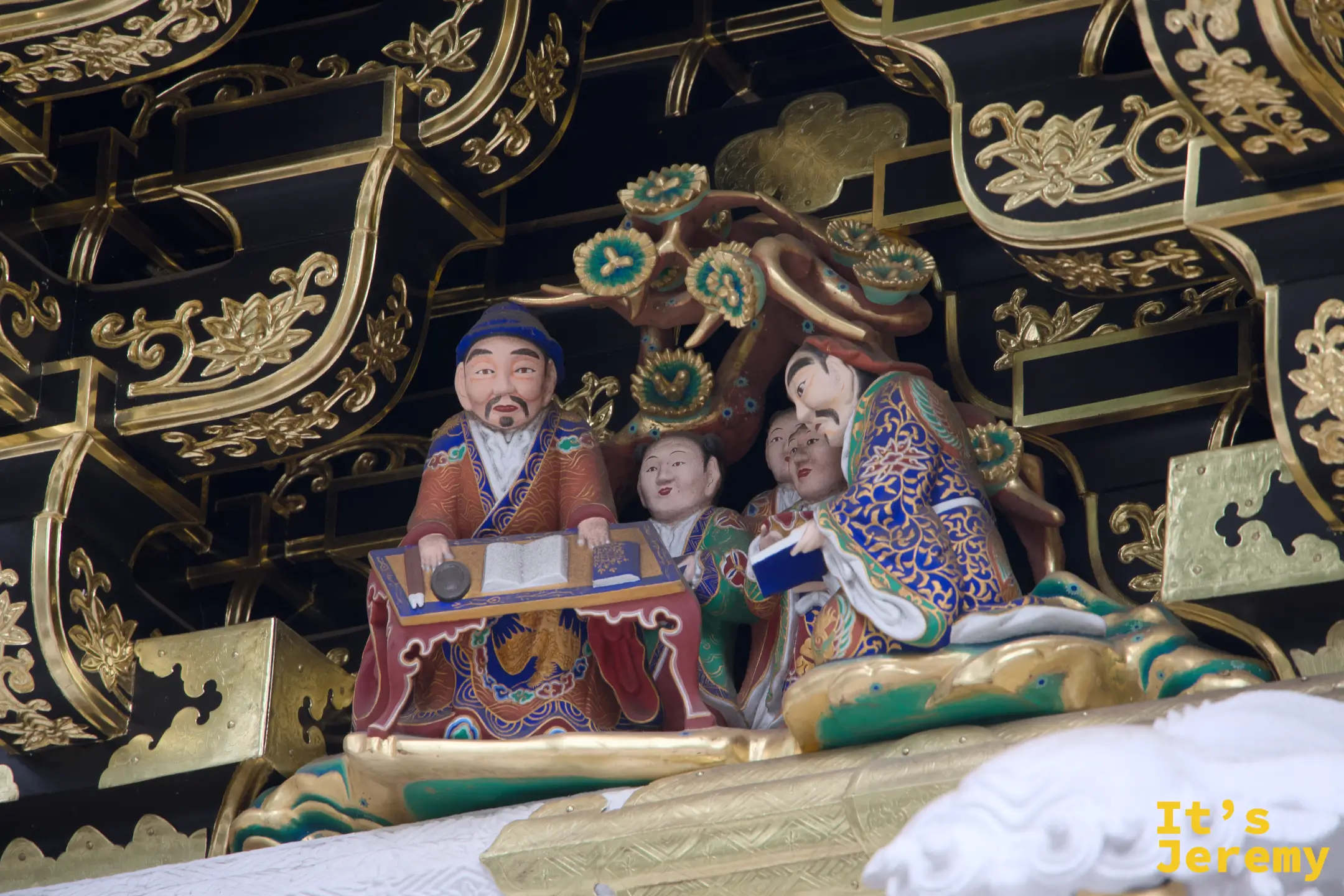 陽明門另一處人物雕刻，三位人物圍坐，或捧書或持物，神情各異