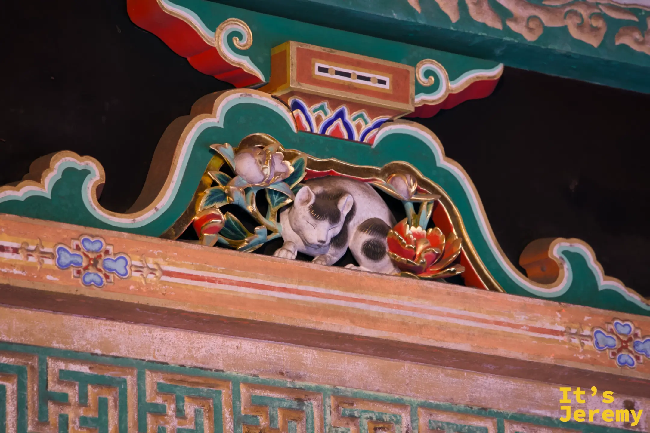 眠り猫彩色木雕，貓身縮成一團，眼睛緊閉，周邊有彩色花卉植物裝飾