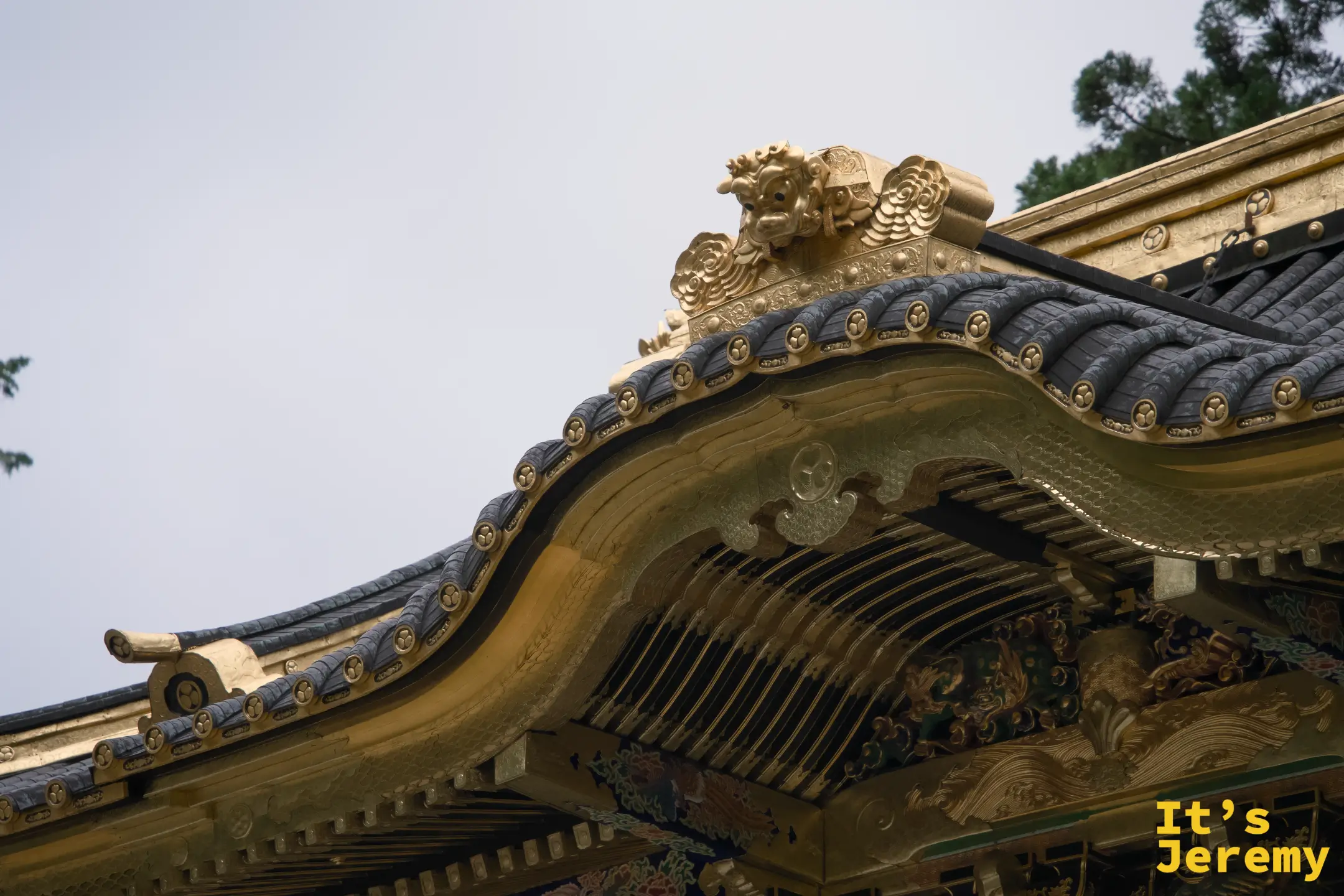 拜殿屋頂屋脊特寫，金色曲線流暢，三葉葵家紋瓦當排列整齊