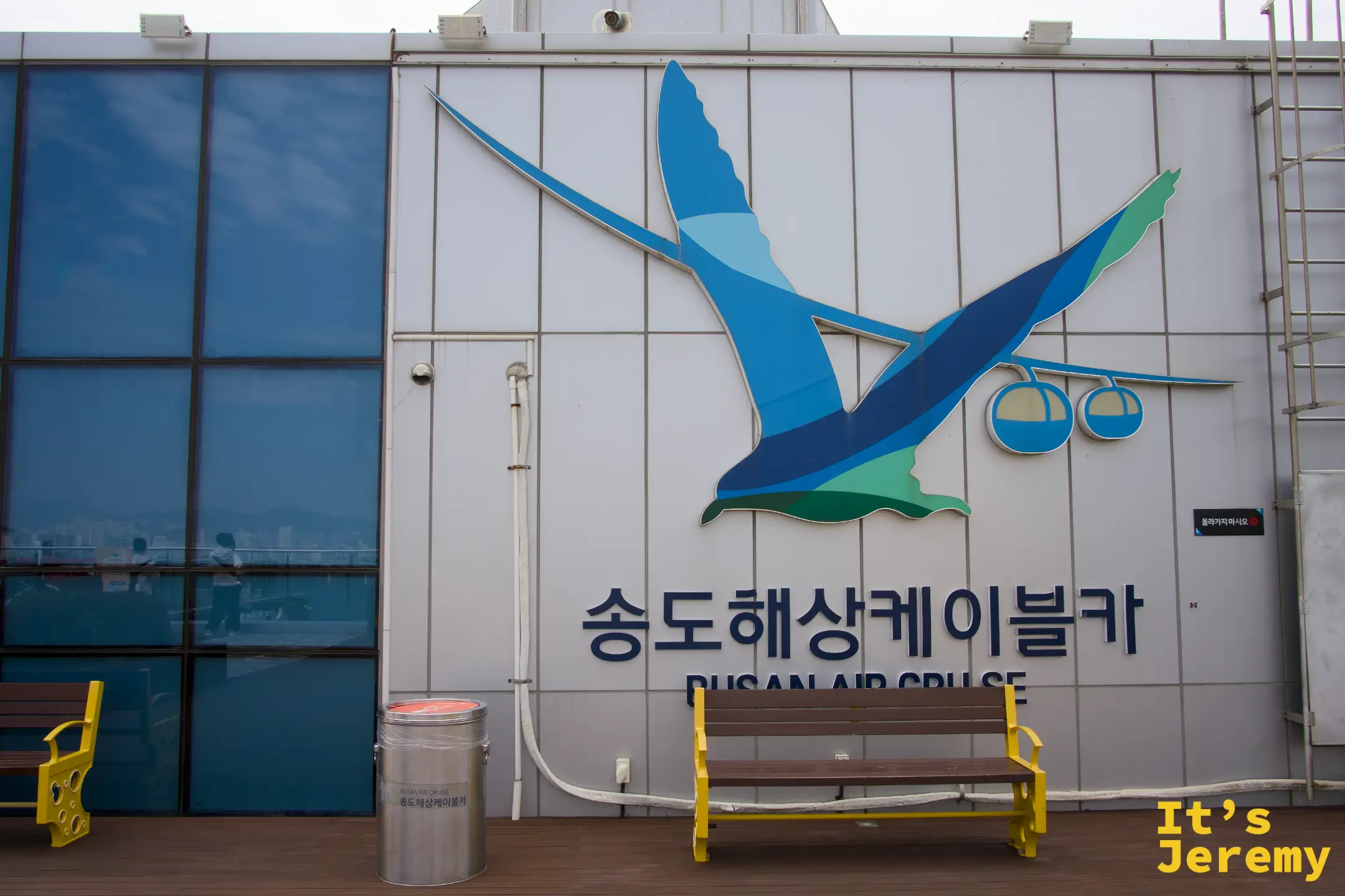 乘車站外觀，站外外牆掛著大鳥造型的 BUSAN AIR CRUISE 立體 logo