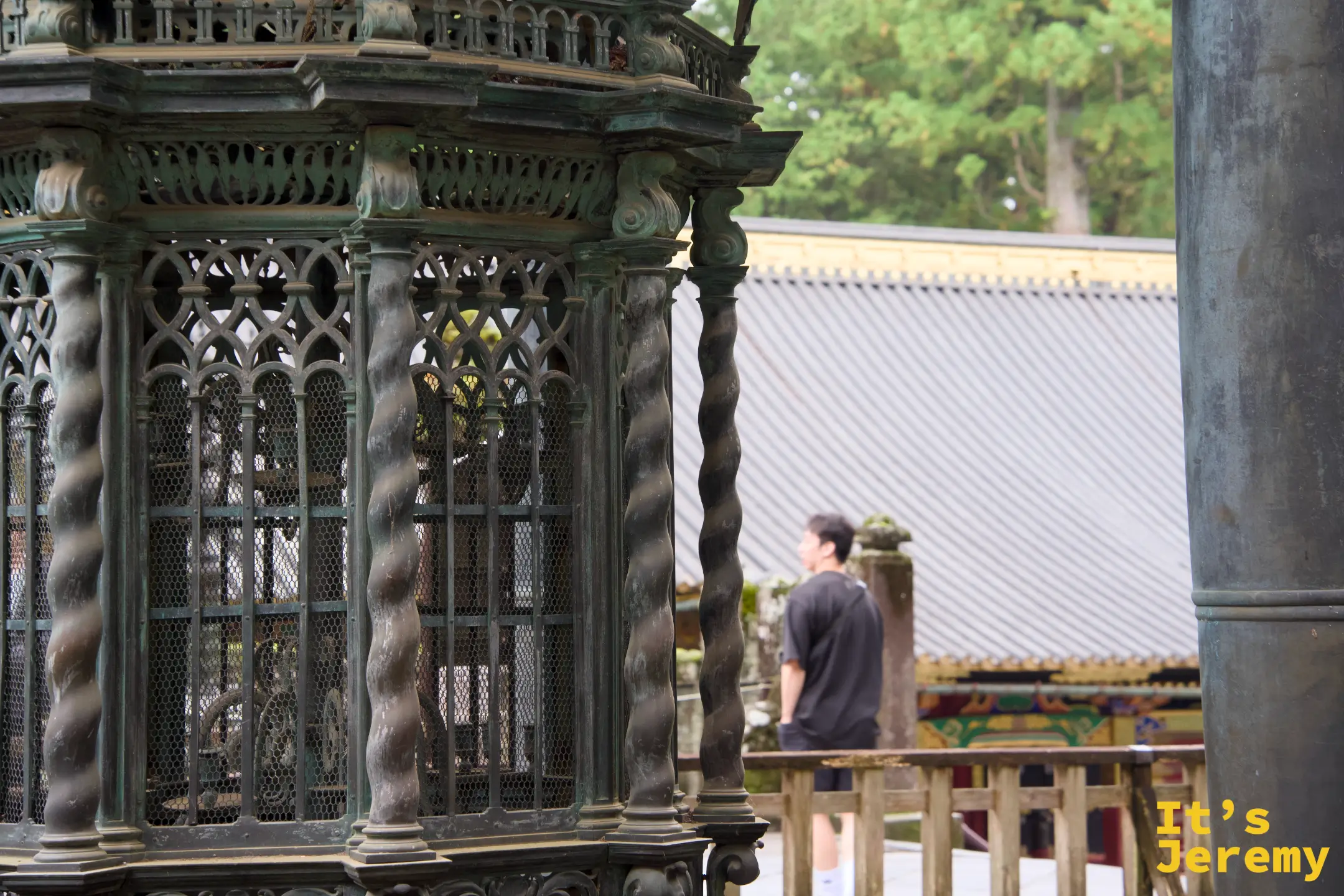 銅製八角形燈籠特寫，鏤空格子設計精細，後方隱約可見神社建築