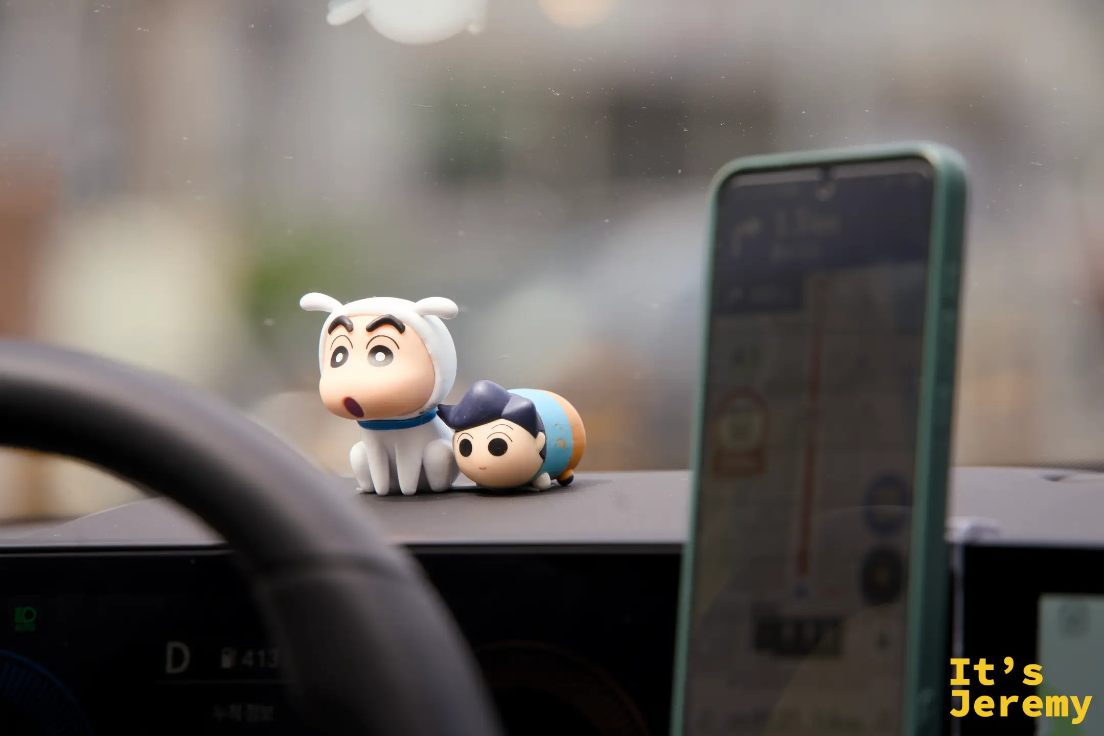 Kakao Taxi 儀表板上的蠟筆小新公仔與另一隻小人偶，旁邊是導航手機架