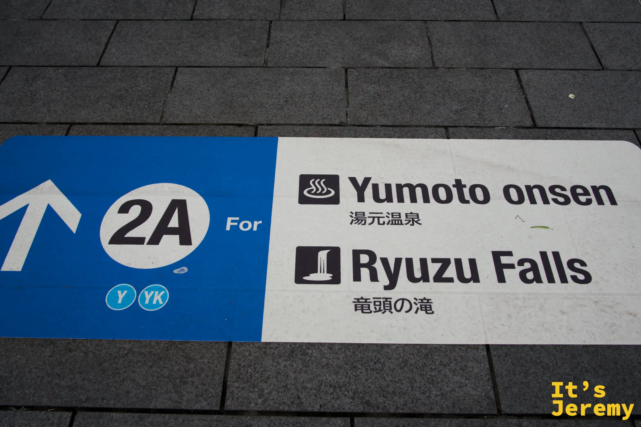 公車站地面指引牌，藍白配色，標出「2A For Yumoto onsen 湯元温泉 / Ryuzu Falls 竜頭の滝」