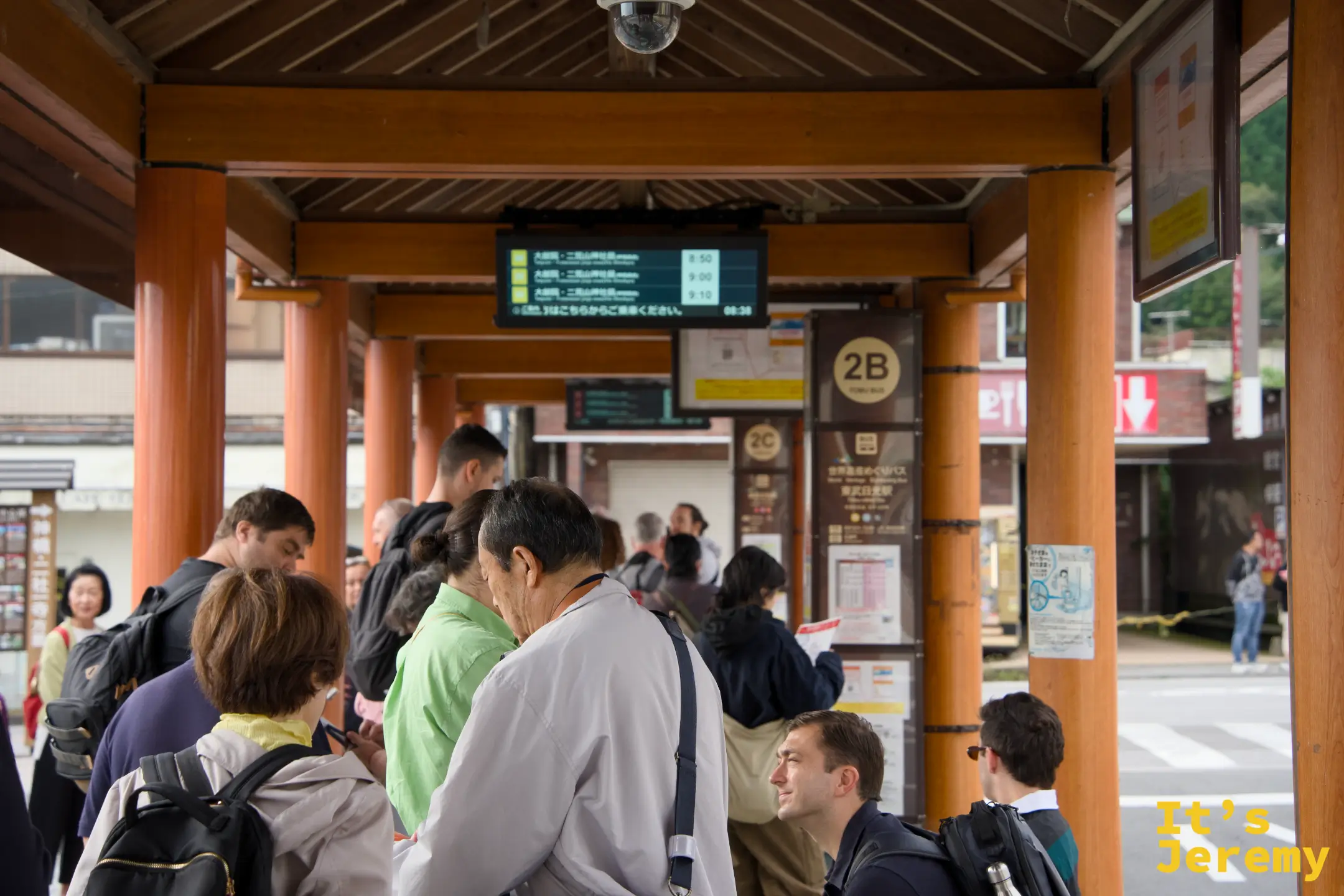 候車亭內旅人熙攘，大家都背著背包等車，出發氣氛濃