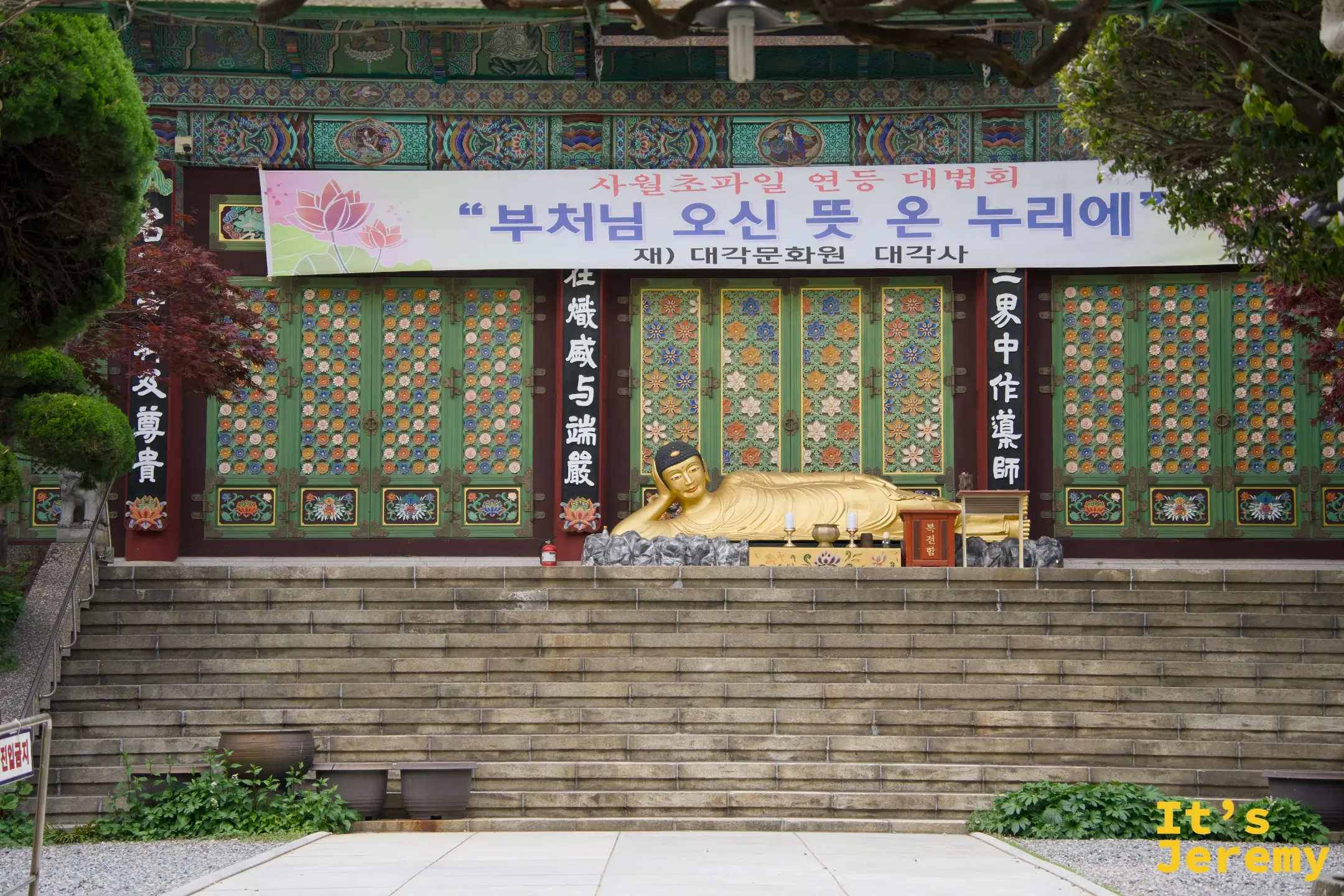 南浦洞路邊的大覺寺臥佛，彩繪木構建築前橫著佛誕節慶標語