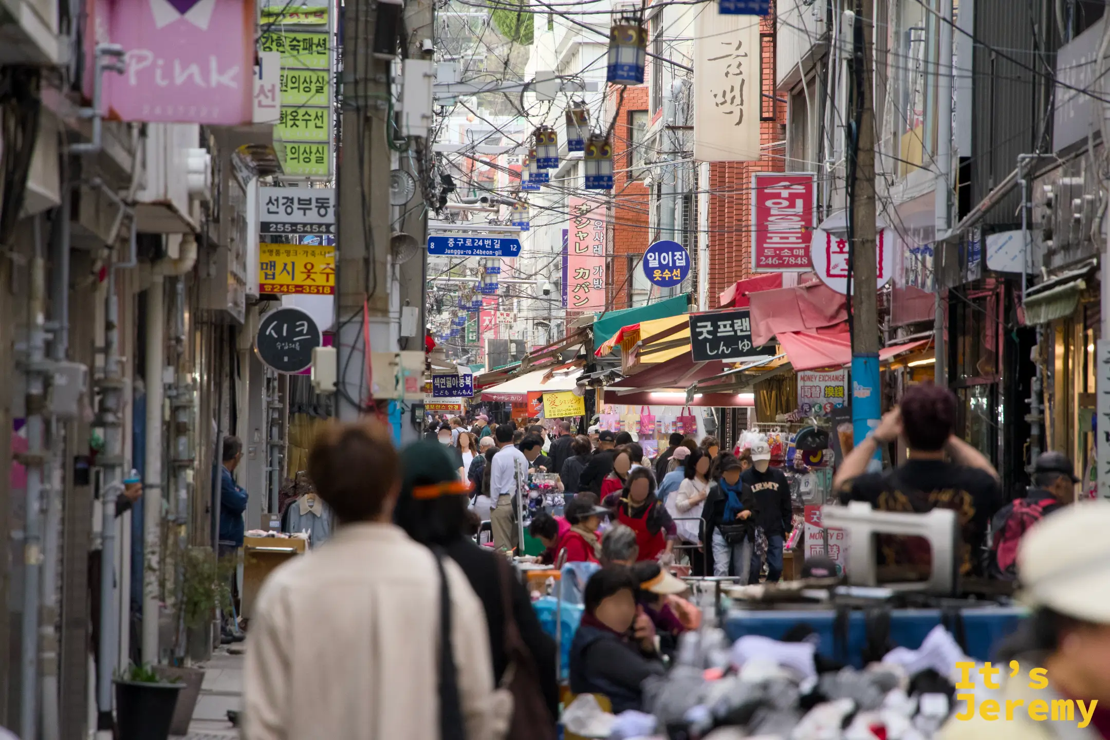 國際市場另一條巷弄，人流從食物攤和服飾攤之間擠過去，攤子、招牌、傘蓋疊成一整面