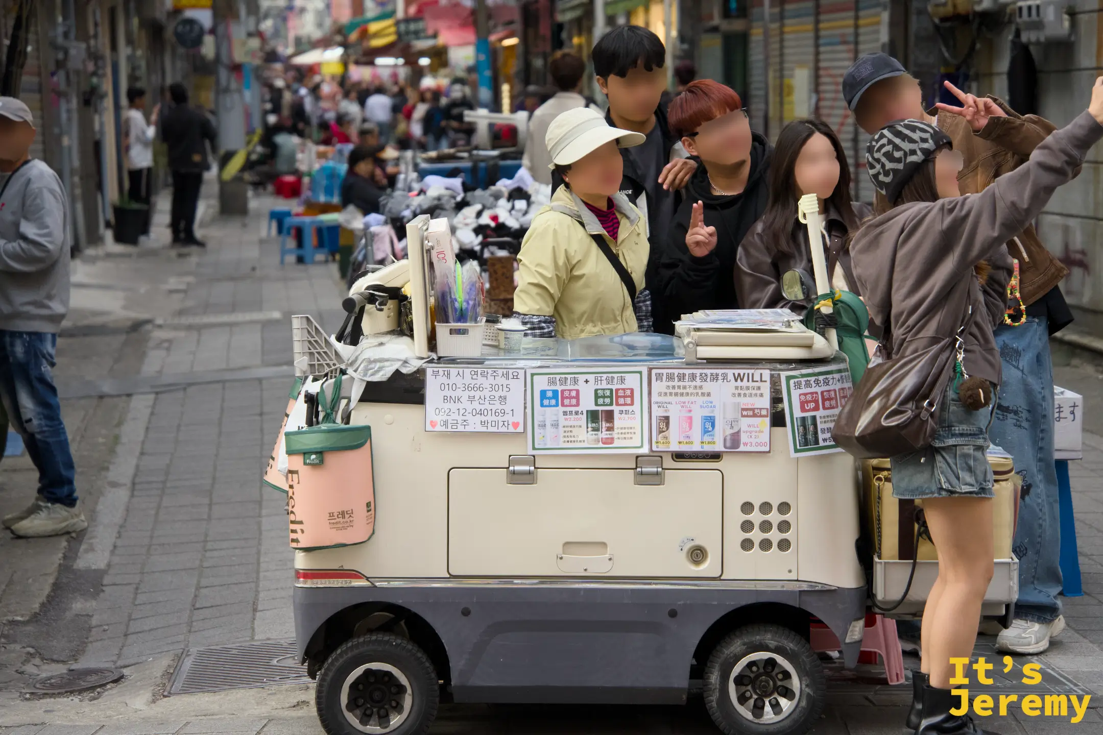 在國際市場的街頭攤車前，大家湊在一起笑著自拍，車上的中日文廣告牌是最釜山的背景