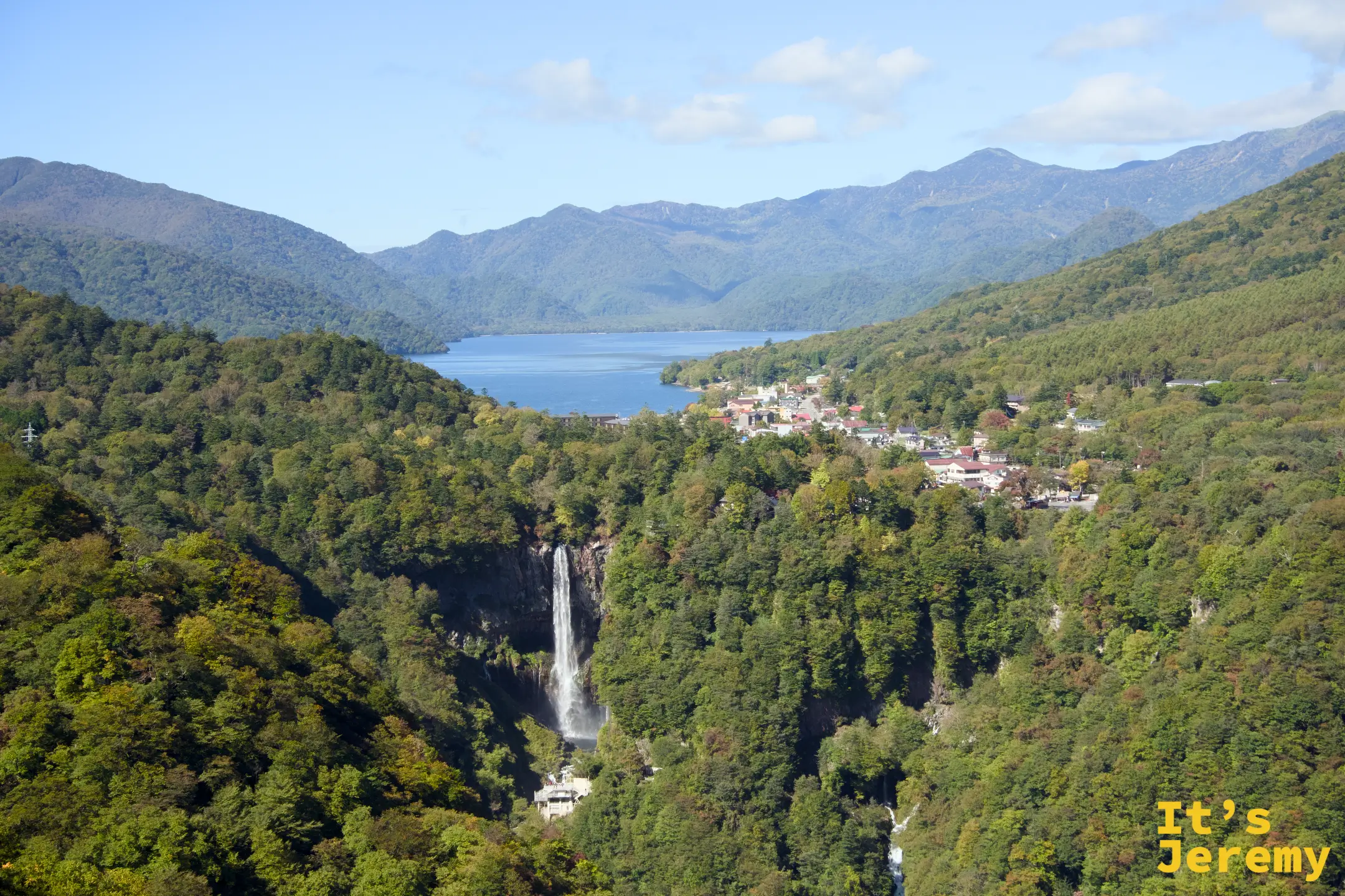 展望台全景，華嚴瀑布從左側山壁直瀉而下，中禪寺湖靜臥在群山懷抱中