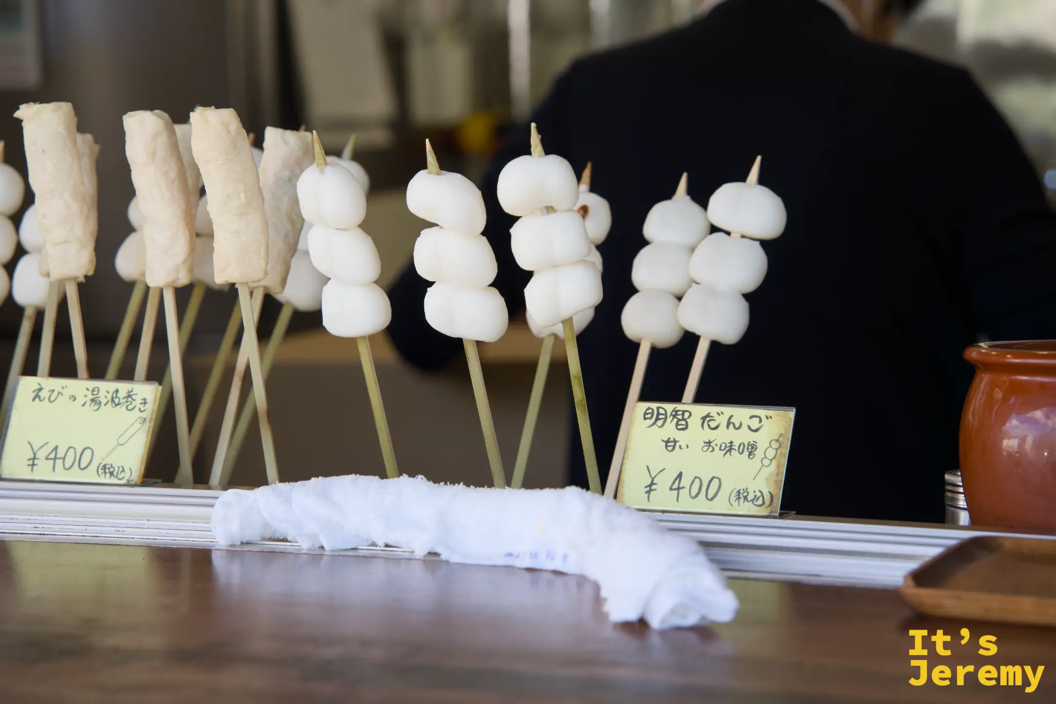 賣店展示串丸子，前方牌子標示「明智だんご 甘いお味噌 ¥400」與「えびの湯波巻き ¥400」