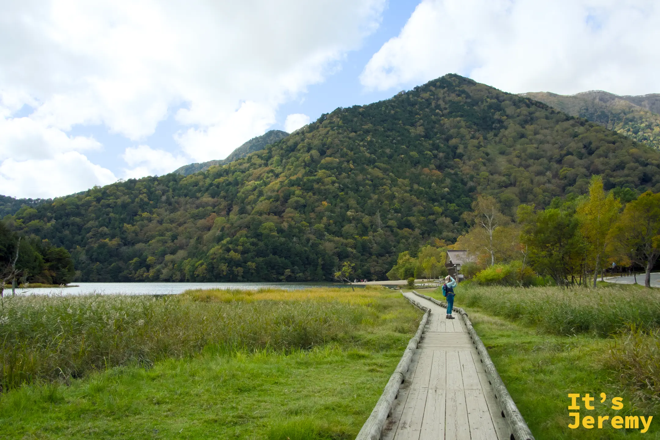 湯之湖邊的木棧道，一位旅人在棧道上拍攝湖景