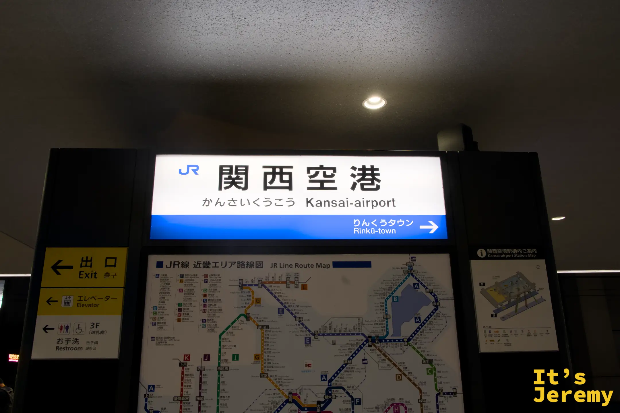 JR 関西空港站站名牌，「関西空港 Kansai-airport」白底藍字清晰標示，下方附近畿路線圖