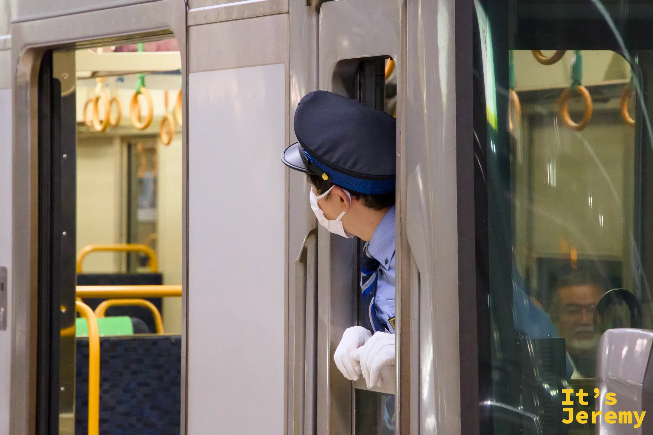 JR 站務員戴白手套從列車車門探頭確認安全的畫面
