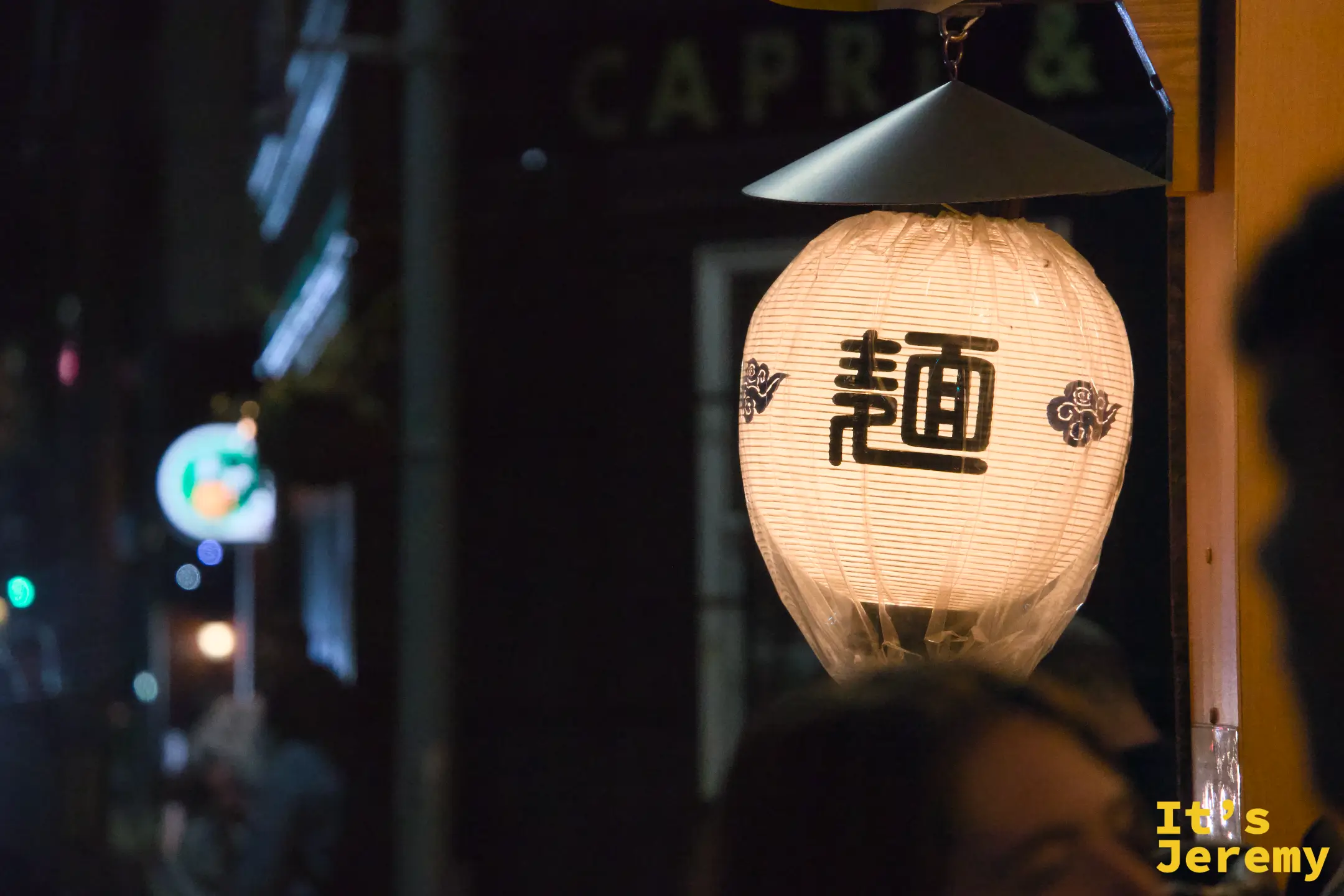 入夜的巷弄，寫著「麺」字的燈籠在黑暗中亮起