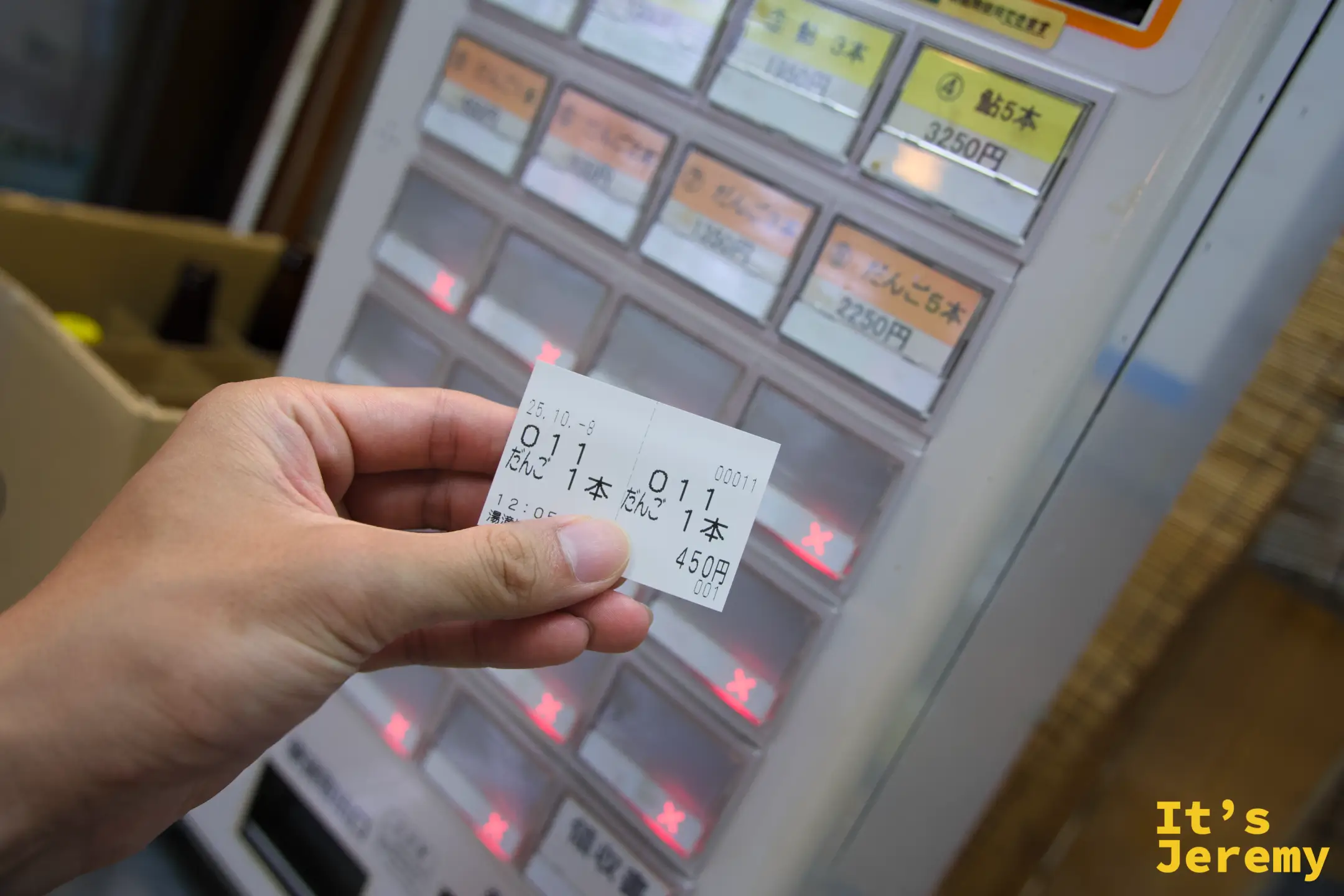 手持剛取出的だんご點餐票，票面顯示「だんご1本 450円」