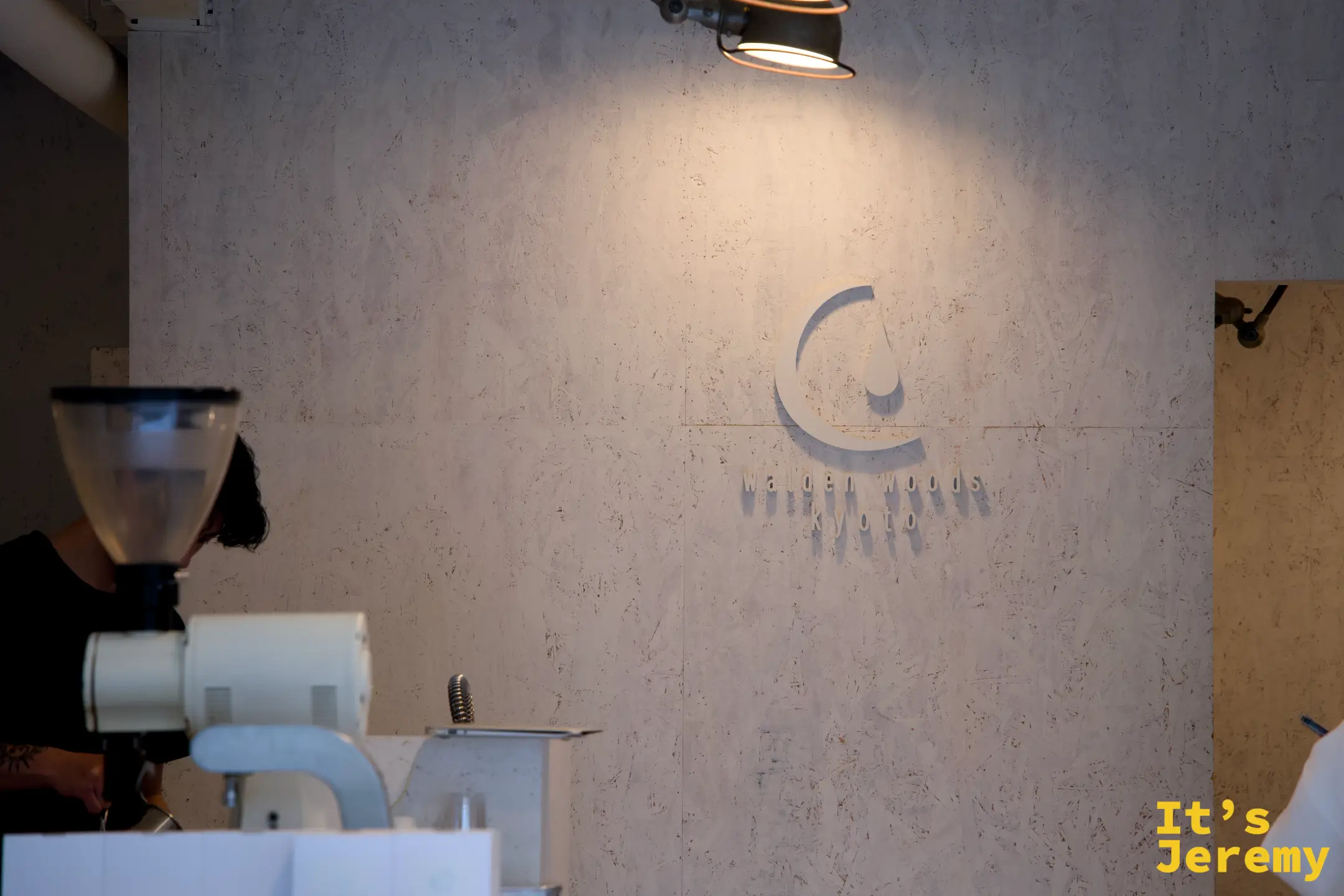 Walden Woods Kyoto logo 牆，烘豆師在一旁專注工作