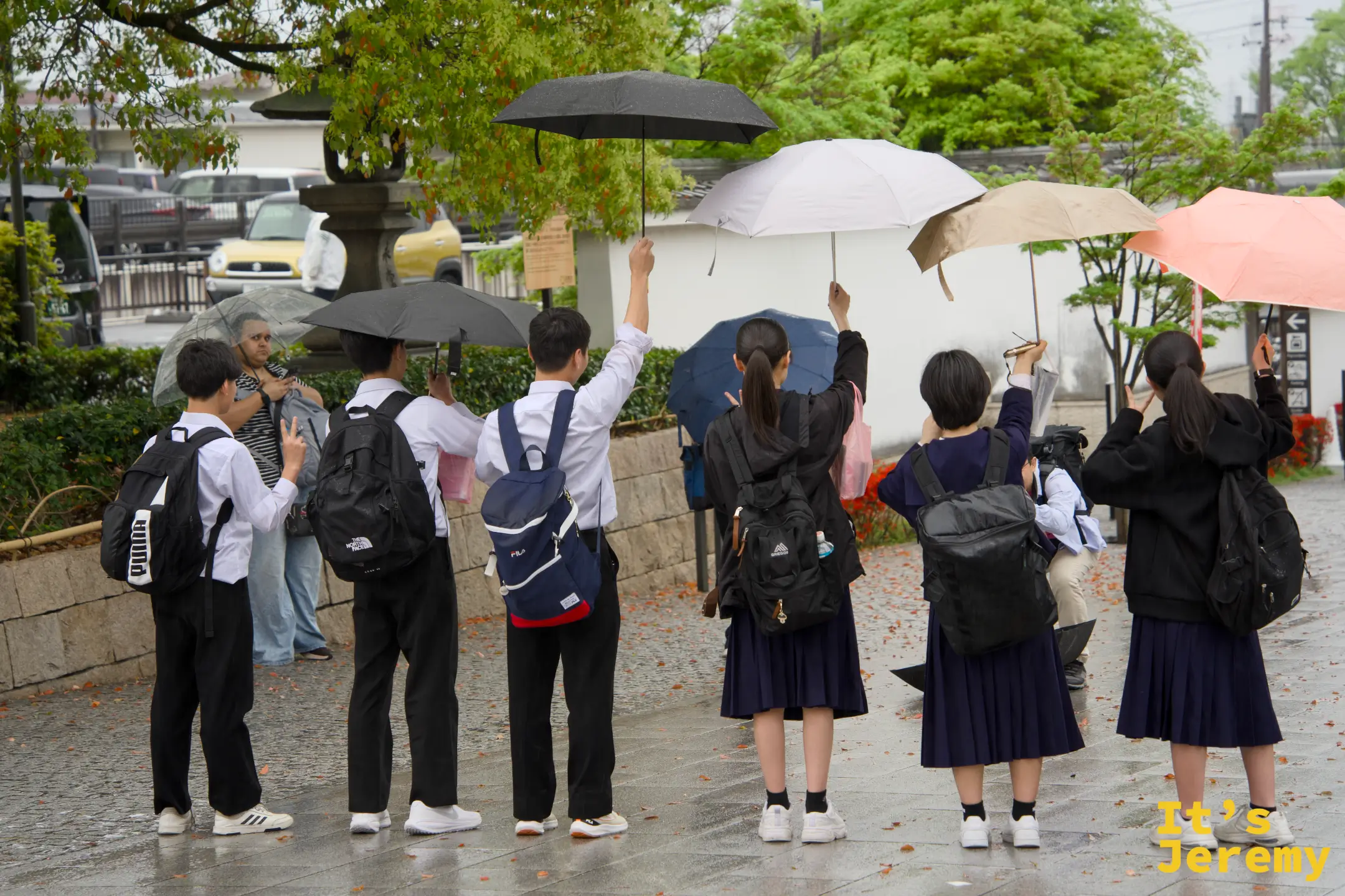 雨天的入口前，穿著制服的學生撐傘拍照留念，修學旅行來伏見稲荷是日本學生的定番行程