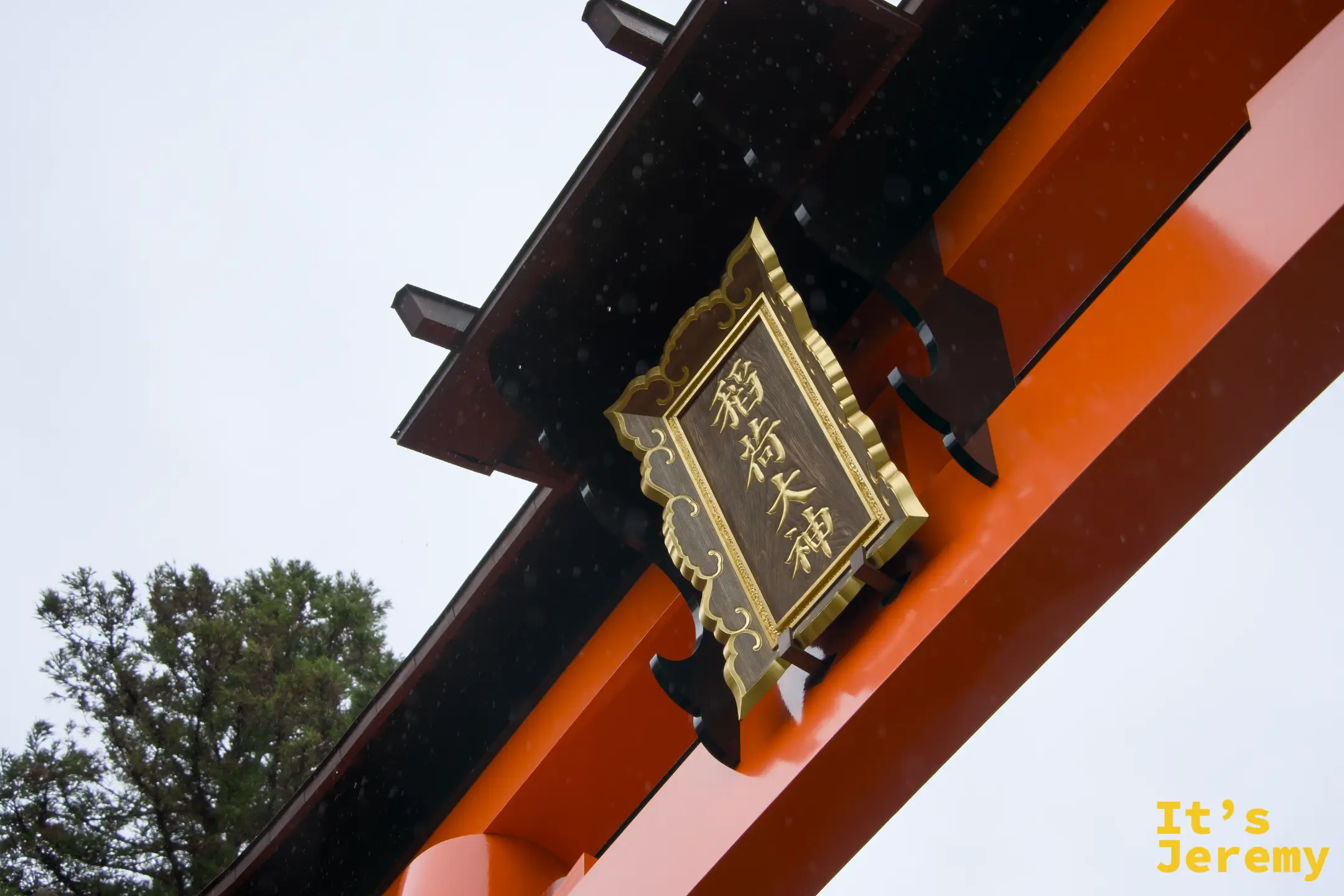 鳥居橫樑上掛著「稲荷大神」金色牌匾，雨滴打在朱紅漆面上，細節極美