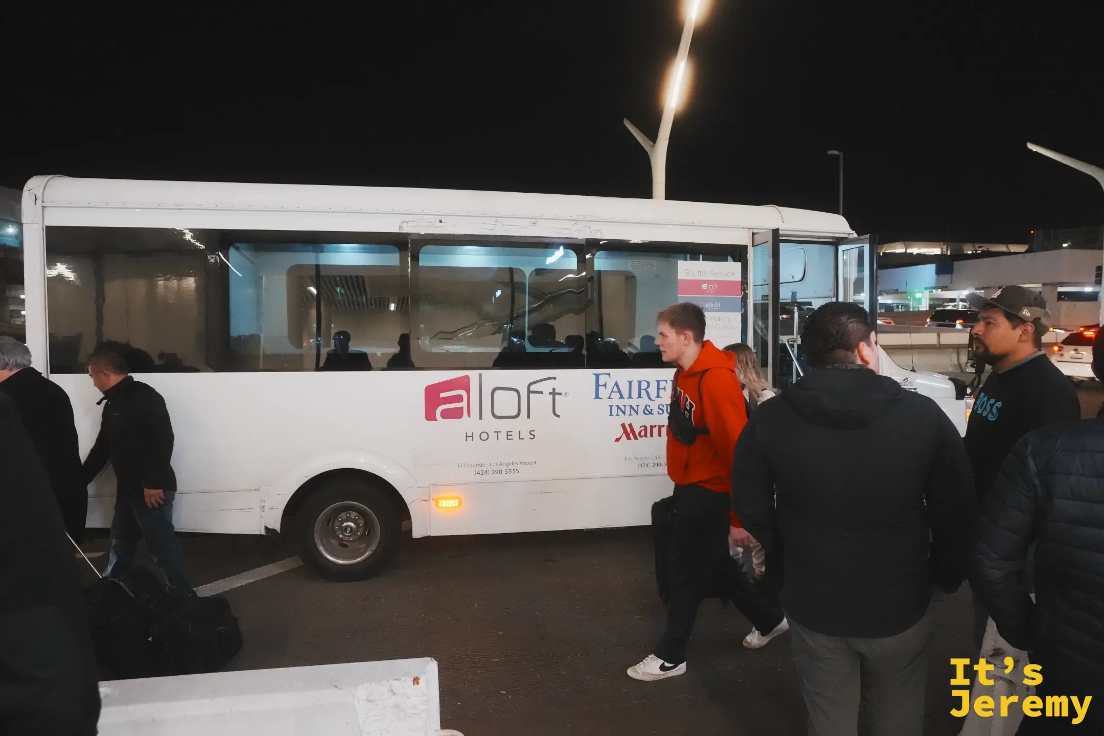 掛著 Aloft、Fairfield 與 Marriott El Segundo 字樣的白色接駁小巴，旅客在夜裡排隊上車
