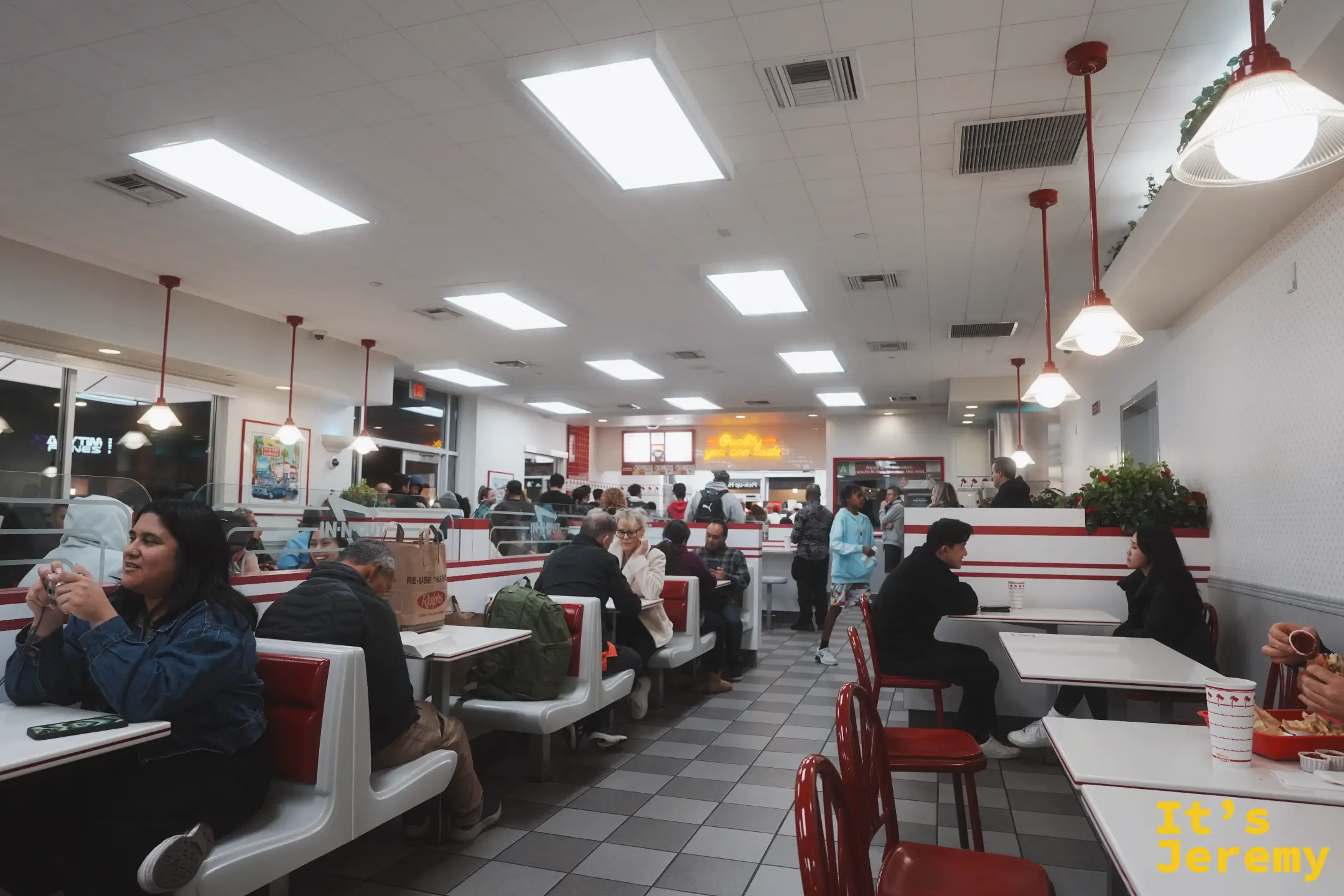 In-N-Out 用餐區內景，紅白色卡座與棋盤格地板，顧客坐滿座位