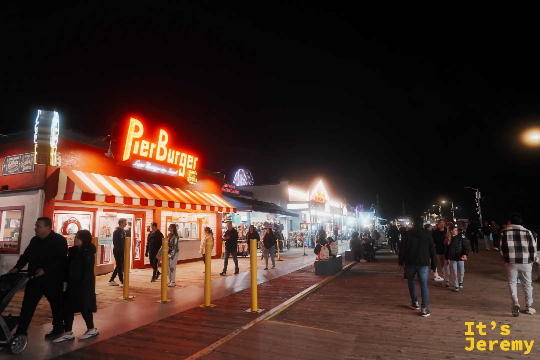 Santa Monica Pier 入夜的木棧道，橘紅色 Pier Burger 霓虹與遠處摩天輪