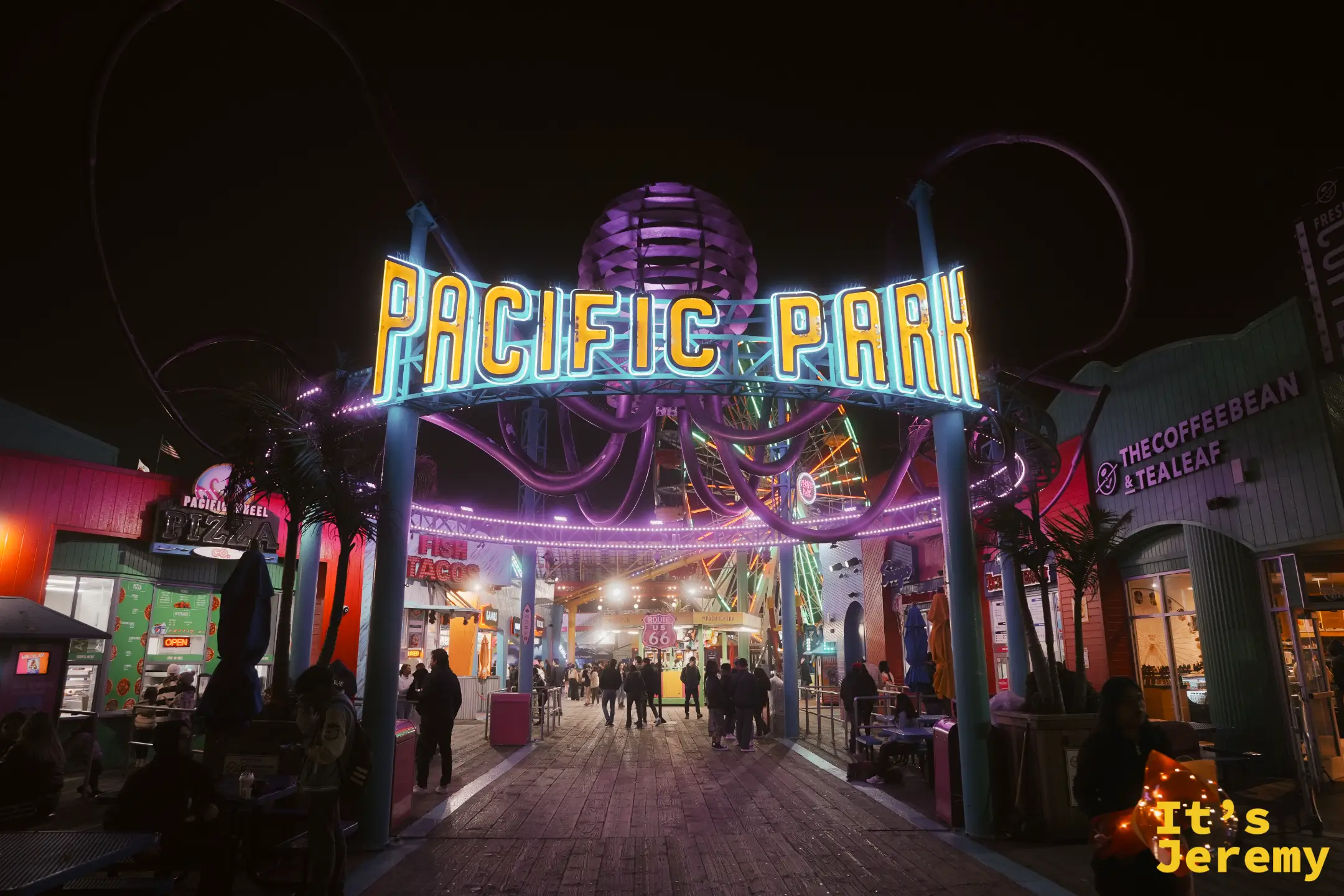 Pacific Park 藍綠色霓虹拱門與門後的摩天輪、遊樂設施