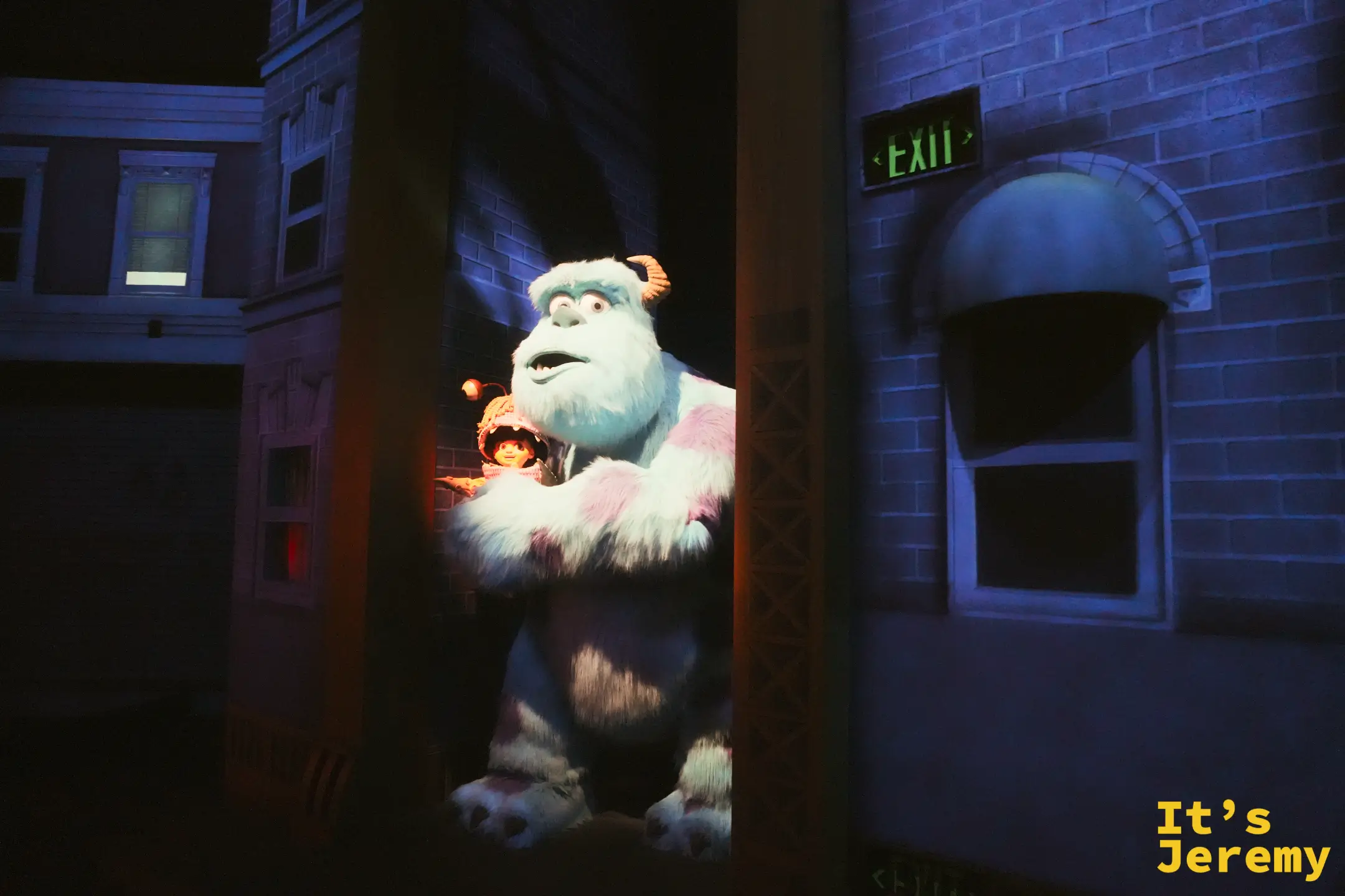 怪獸電力公司室內場景，毛怪 Sulley 抱著喬裝的阿布躲在門後