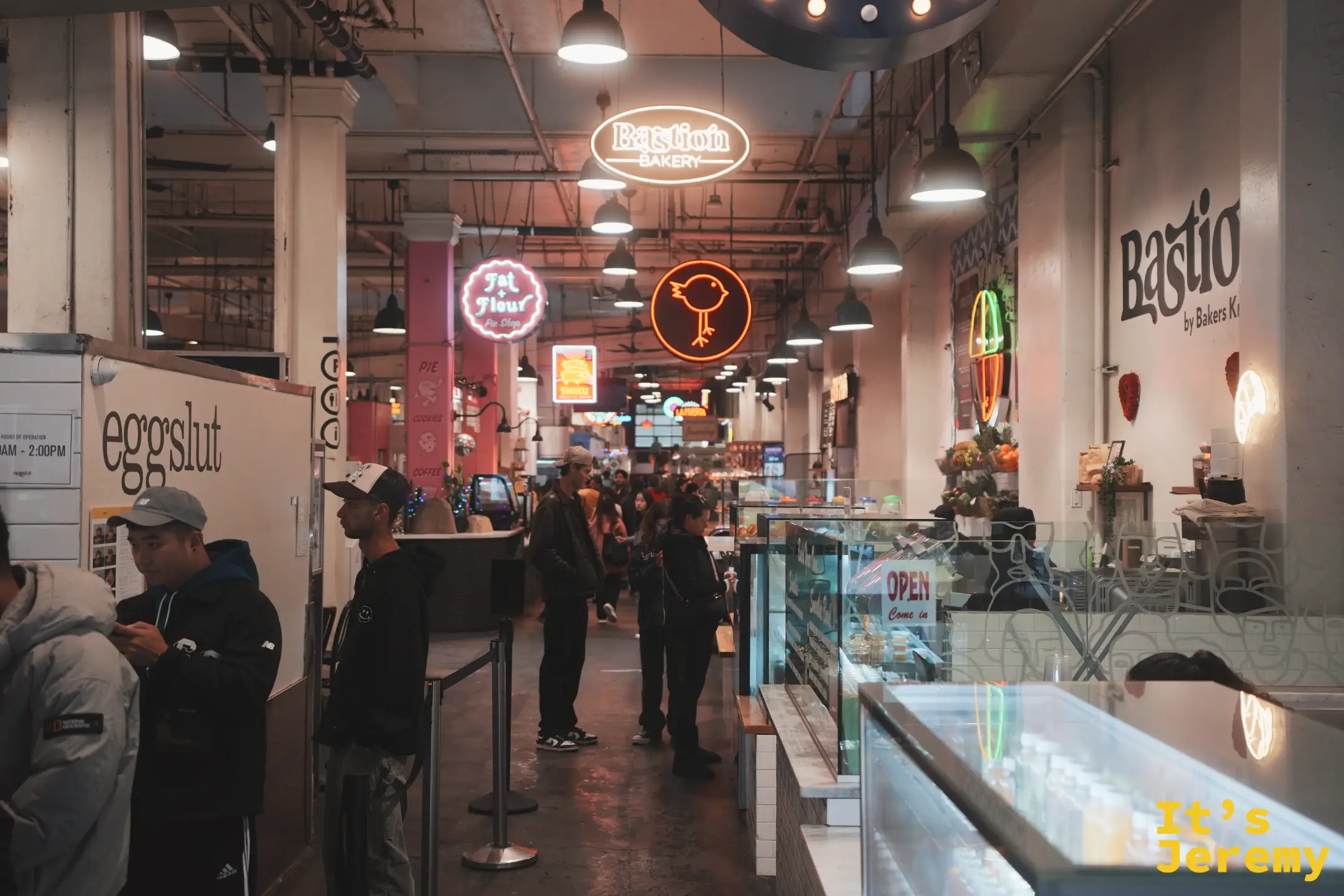 Eggslut 攤位排隊人潮與白色招牌，旁邊是 Bastion Bakery 等霓虹
