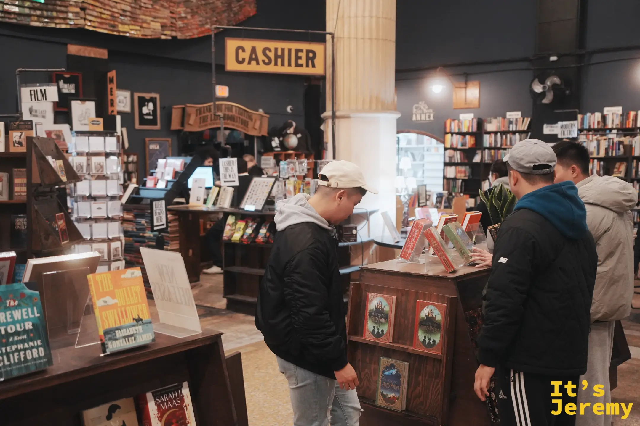 The Last Bookstore 一樓黃色 CASHIER 燈箱與新書、哈利波特特別版的展示區，遊客在挑書